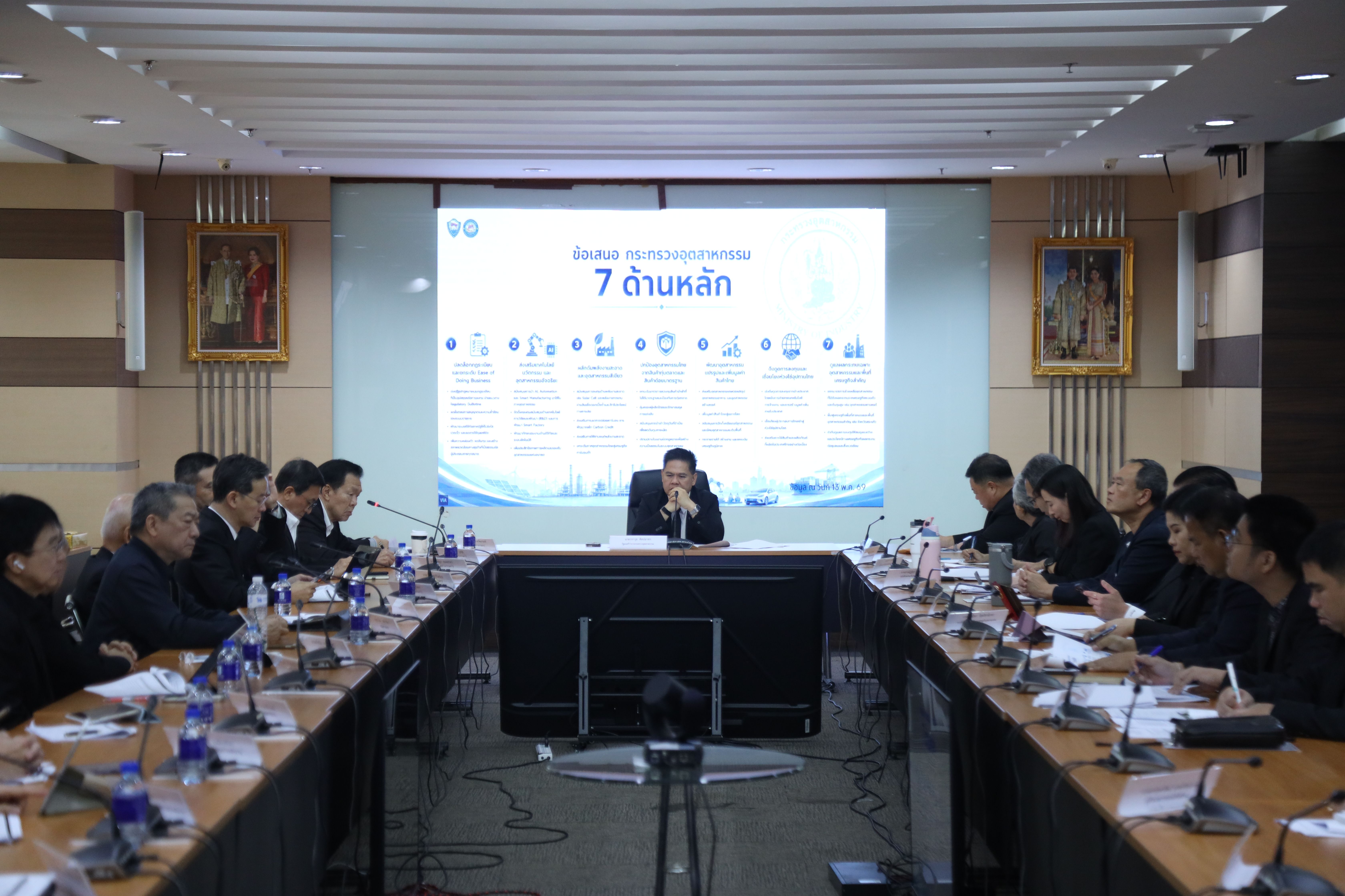 Professionals attend a meeting in a conference room with a presentation on a large screen.
