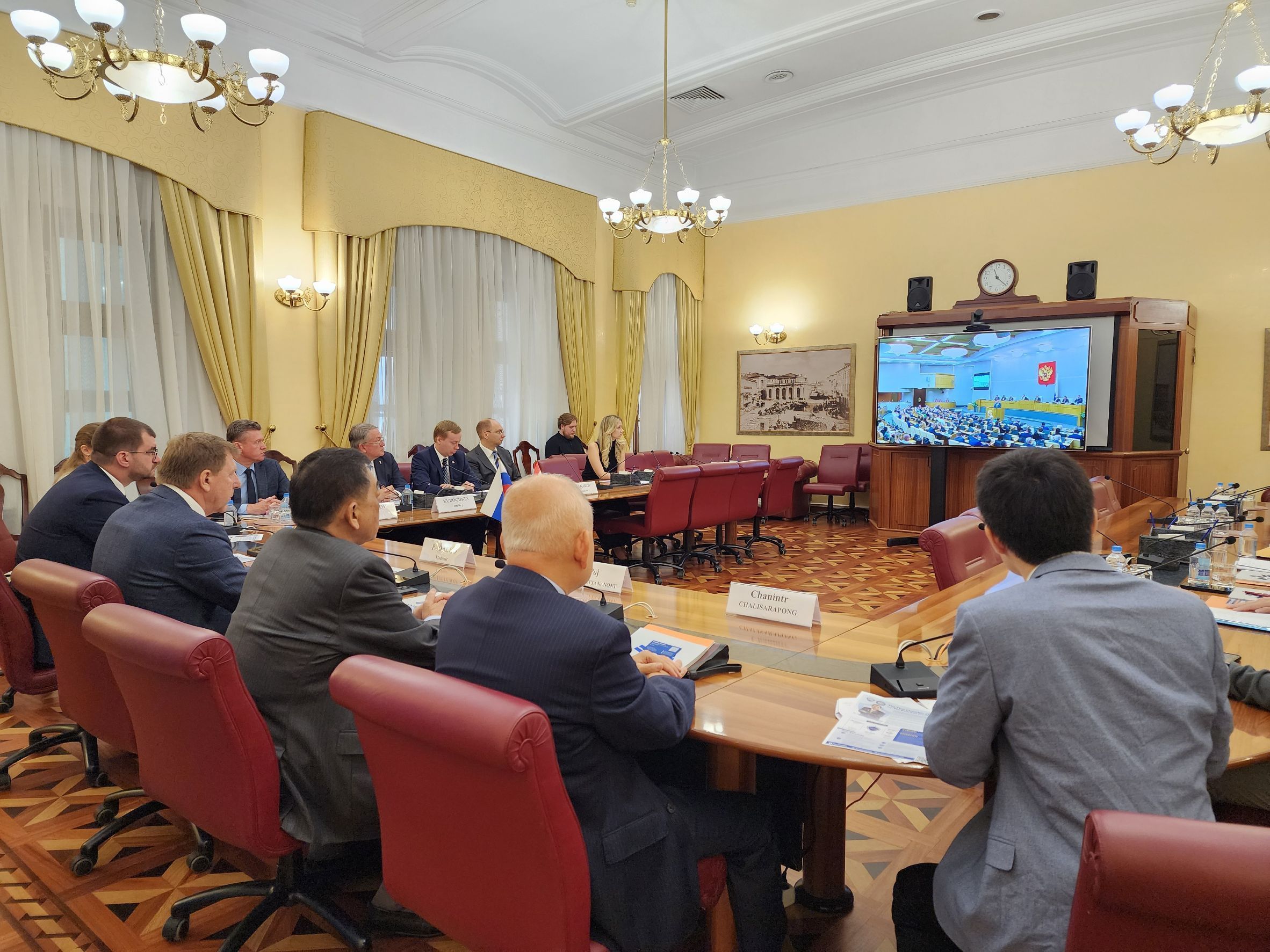 Business meeting with attendees observing a large screen in a formal conference room.
