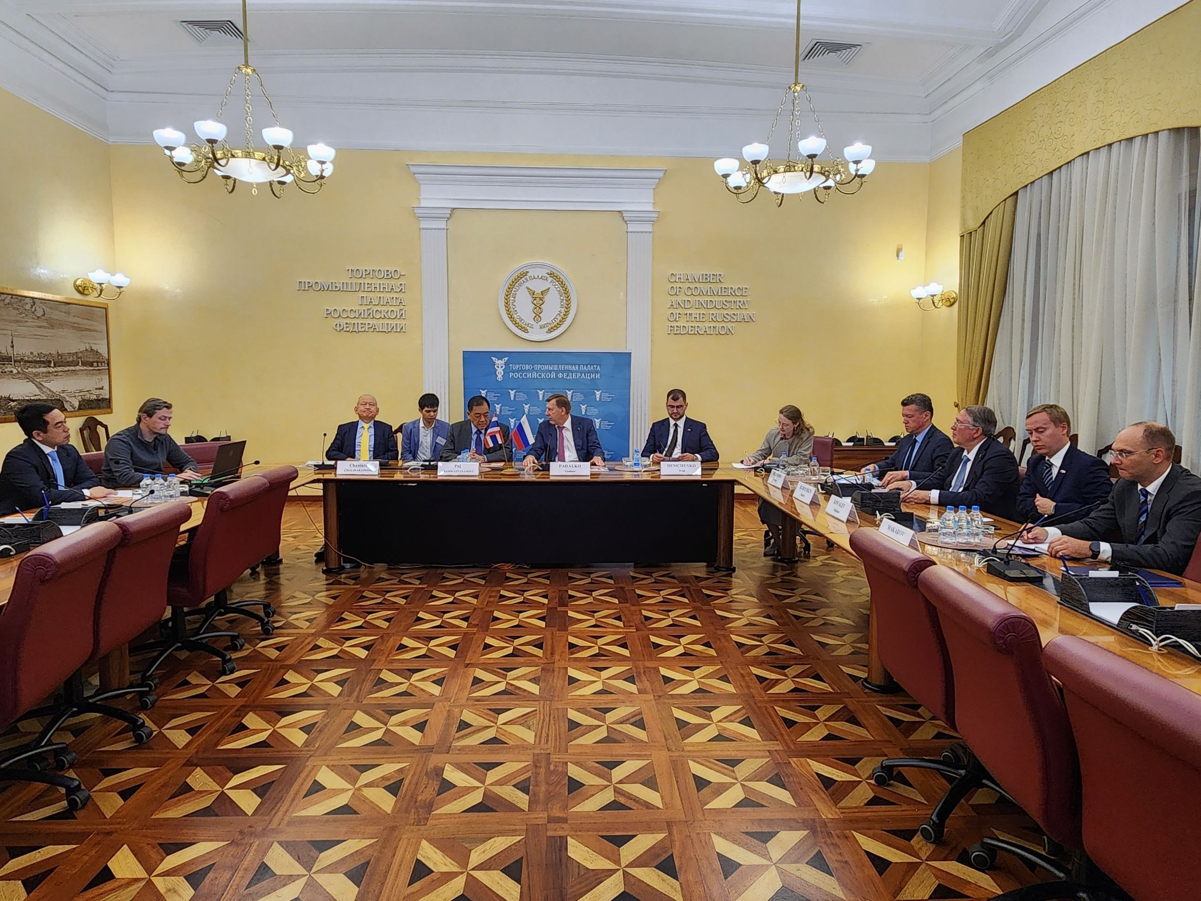Group of professionals seated around a large table in a formal meeting room.
