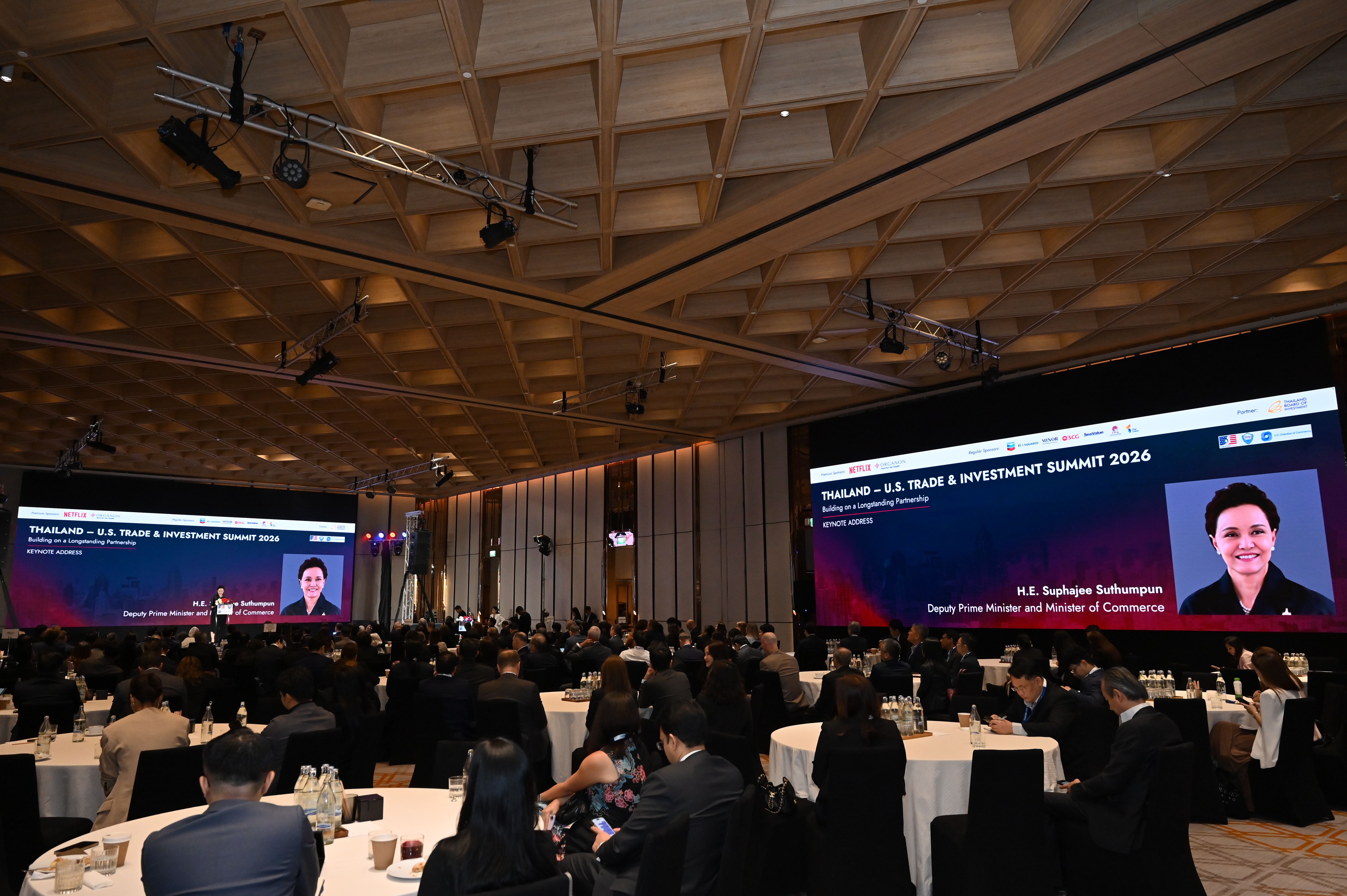 Conference hall with many attendees and large screens displaying a speaker and presentation.
