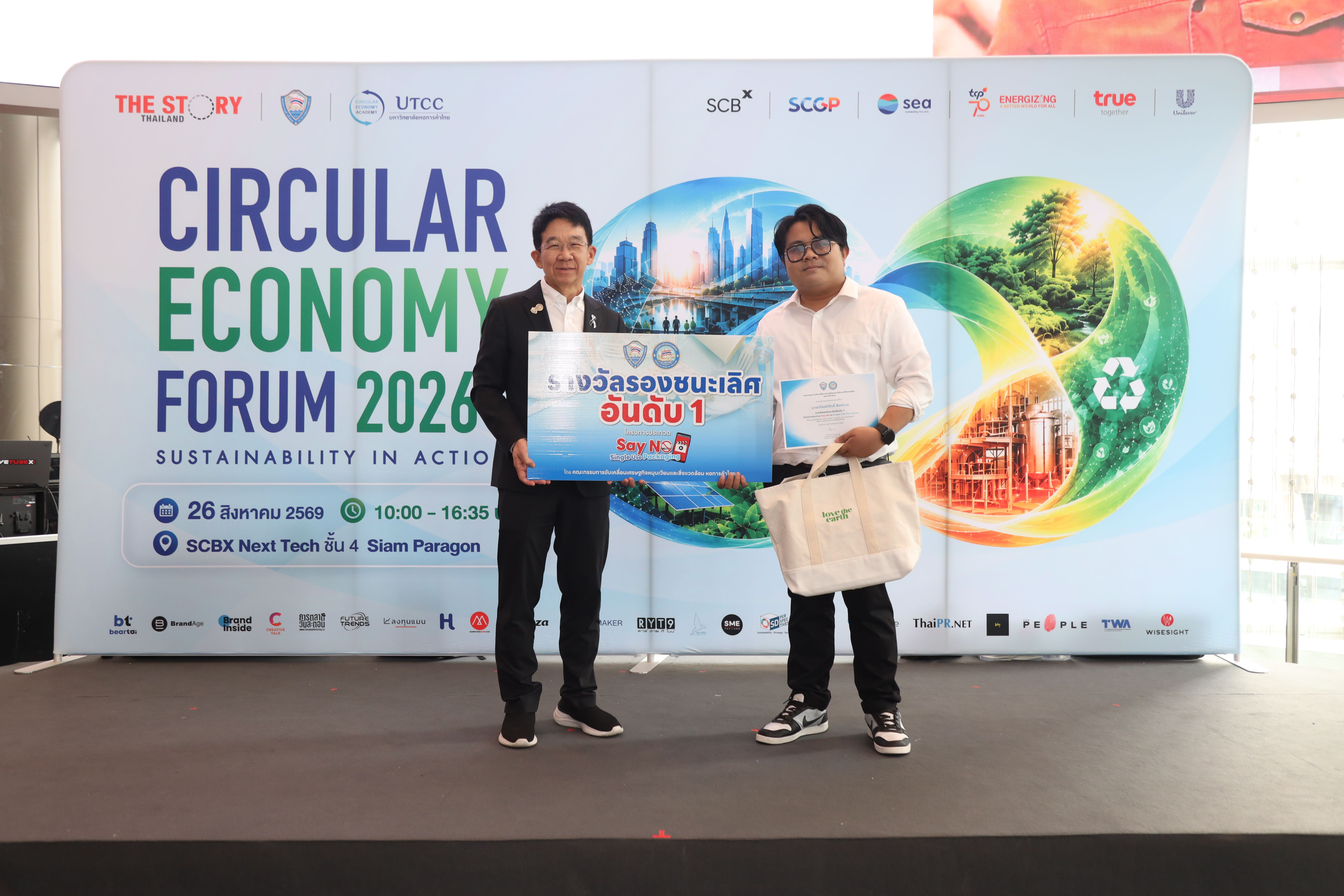 Two men on stage holding a presentation board at the Circular Economy Forum.