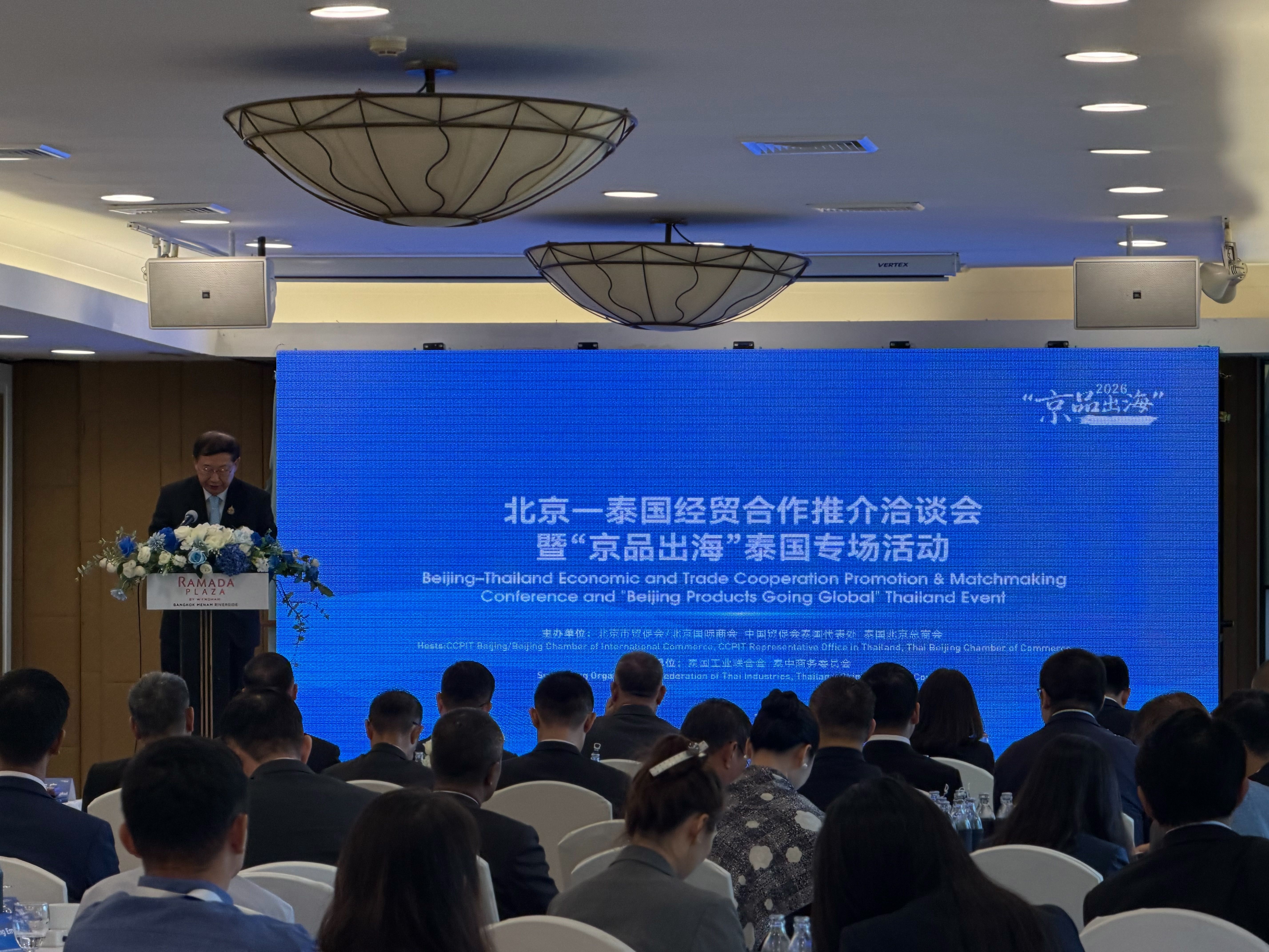 Man speaking at podium before screen displaying conference text to an audience.