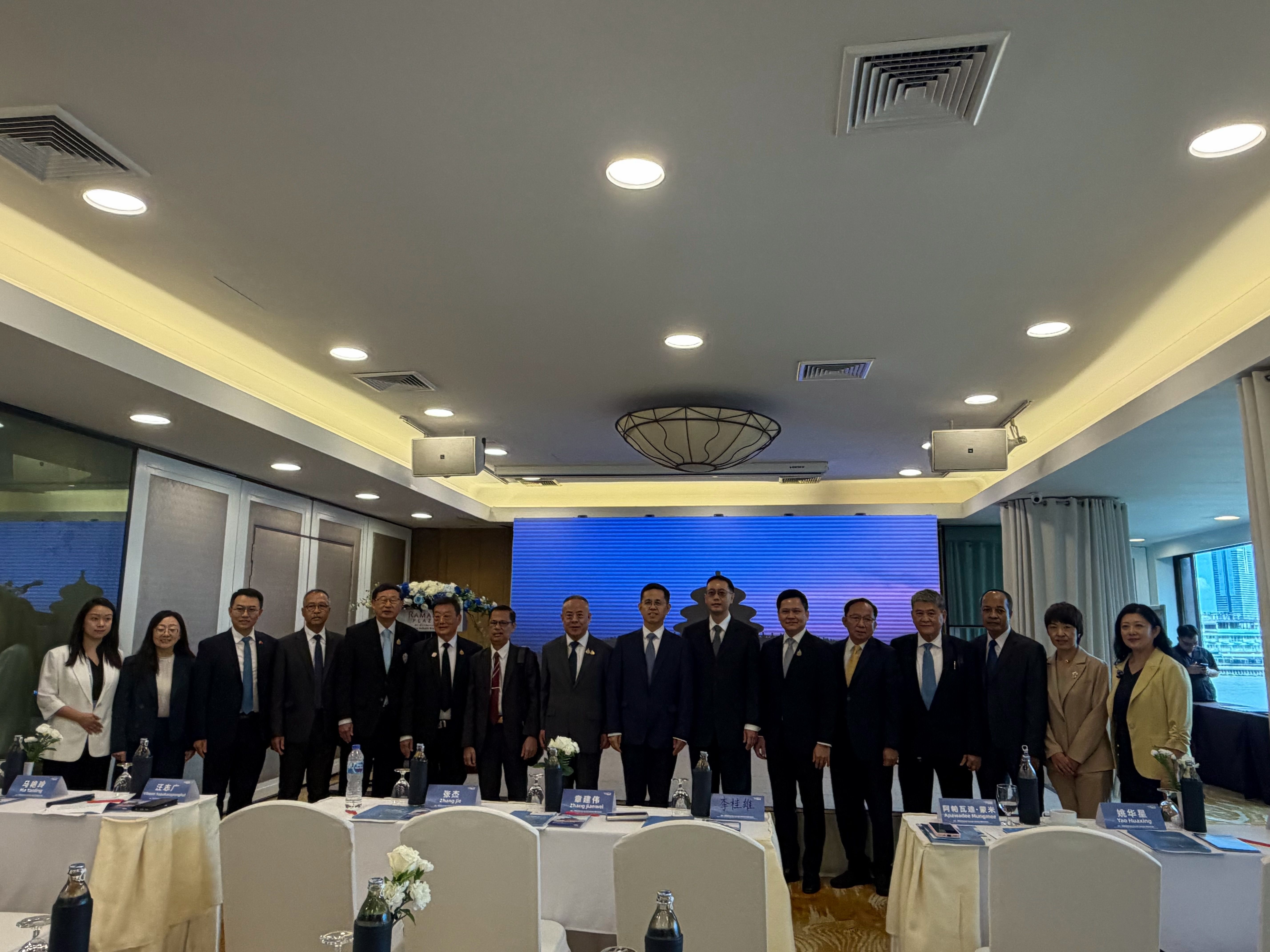 A diverse group of professionals in suits stands together in a well-lit conference room.