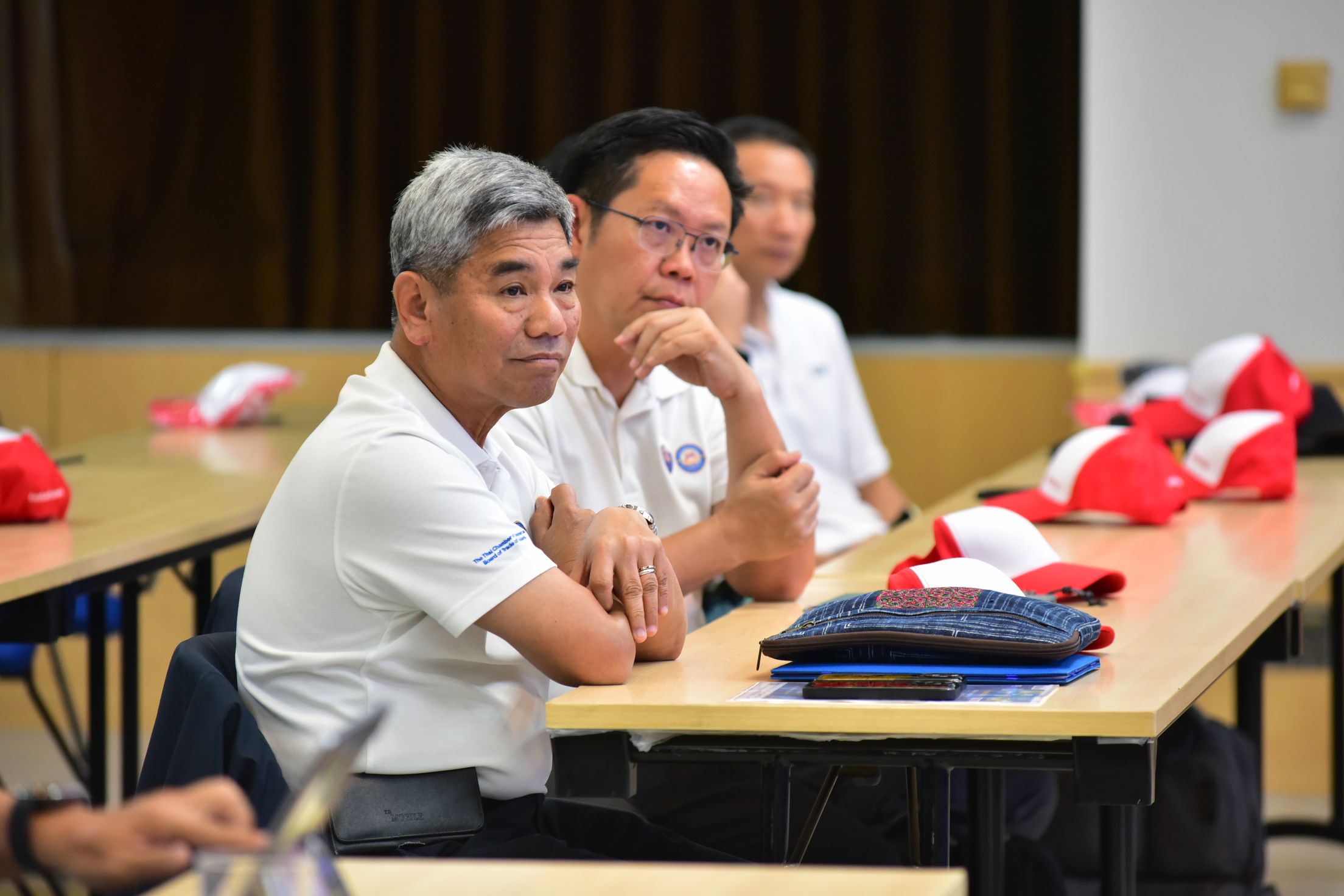Two men attentively listen at a table during a professional meeting.