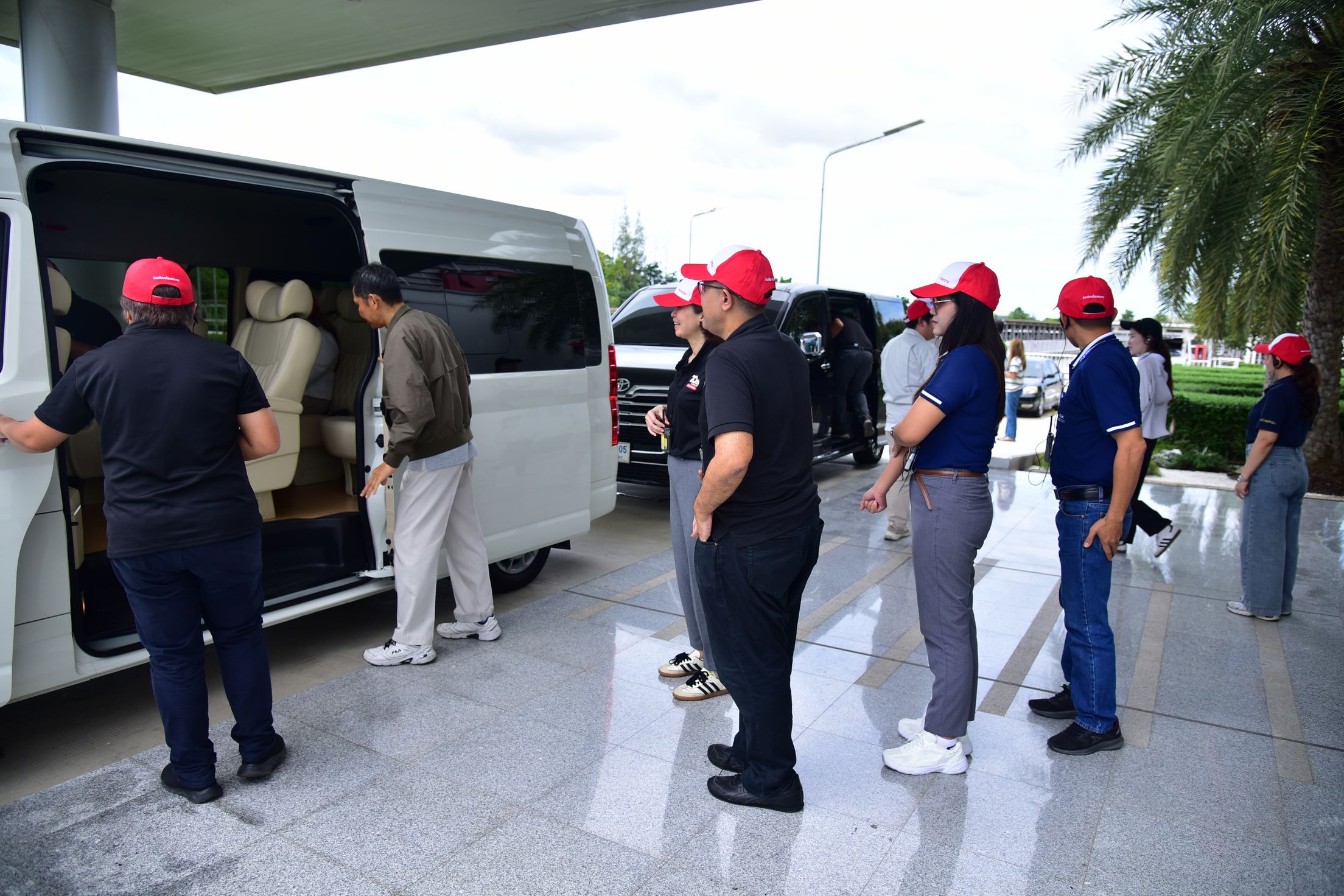 Group of people in red caps boarding a white passenger van.