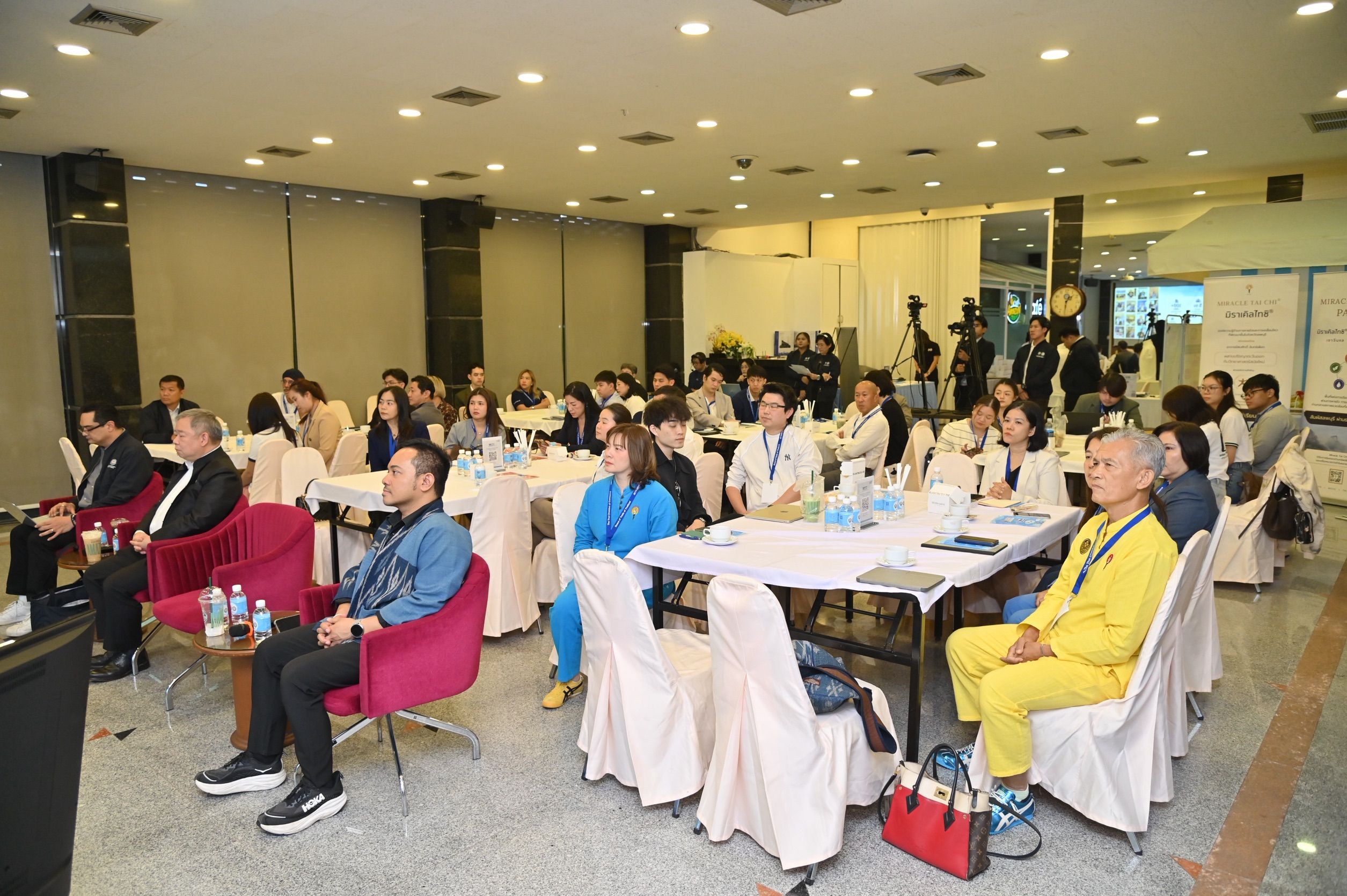 Diverse group of attendees listens intently at an indoor conference event.
