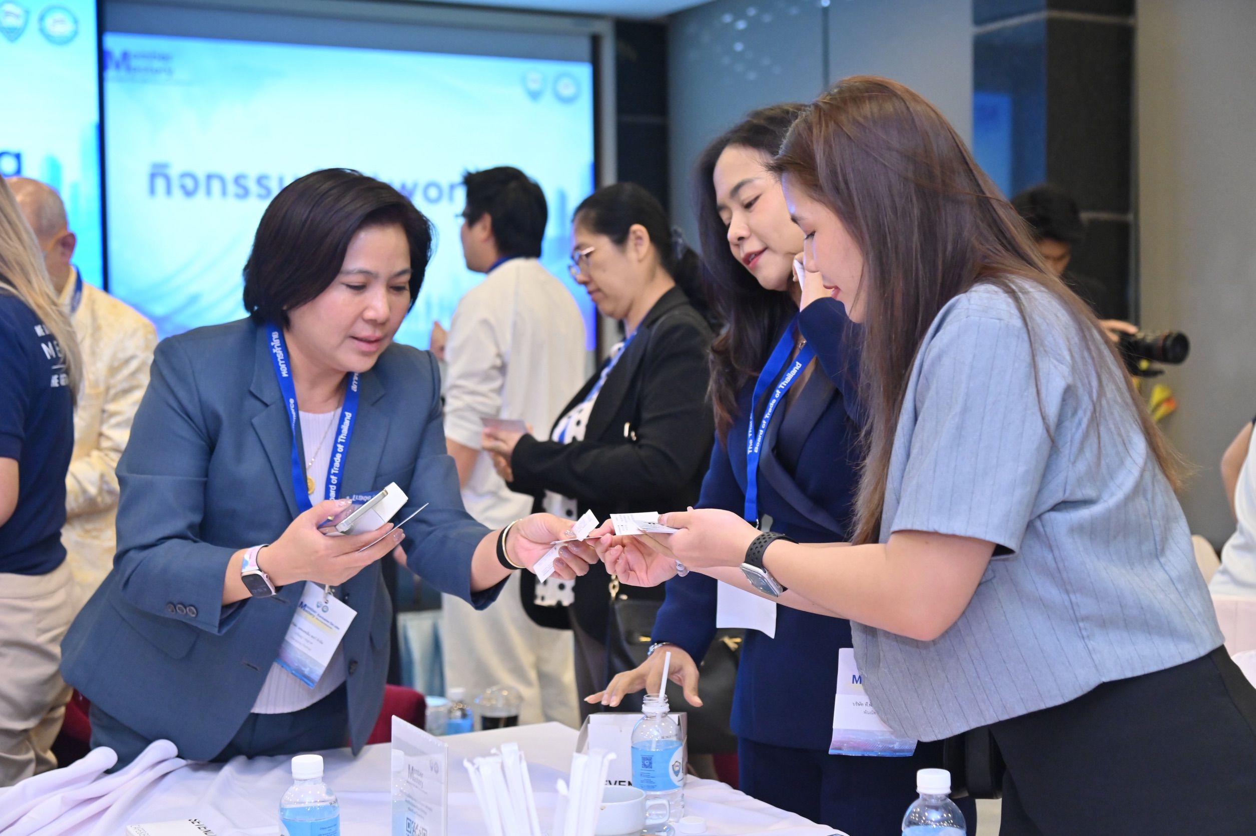 Woman in blue suit hands small items to another woman at a professional event.