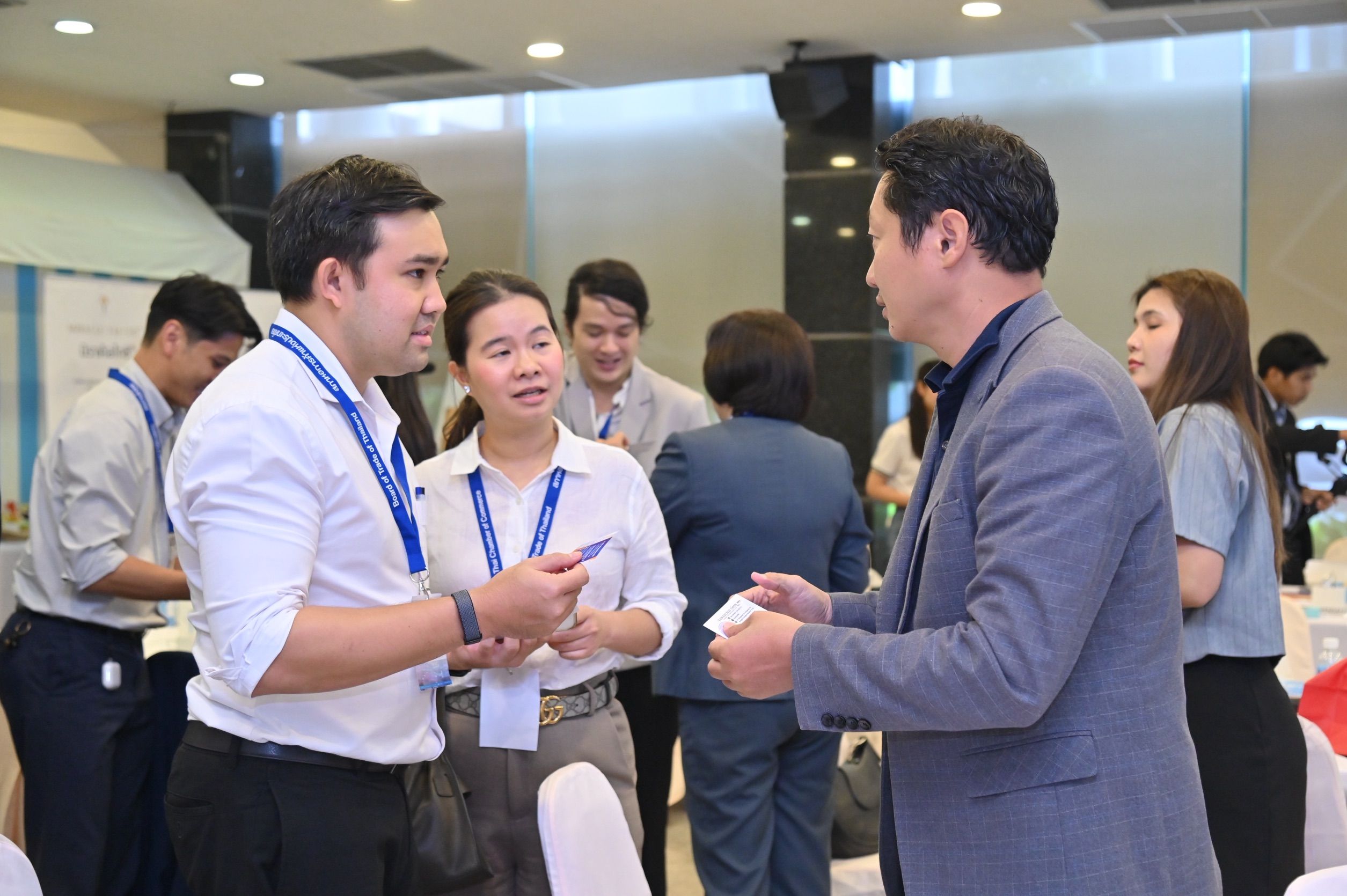 Three professionals engage in conversation during a networking event indoors.
