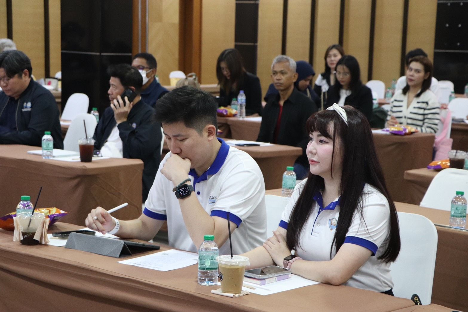 Man and woman seated at a table, taking notes during a conference.