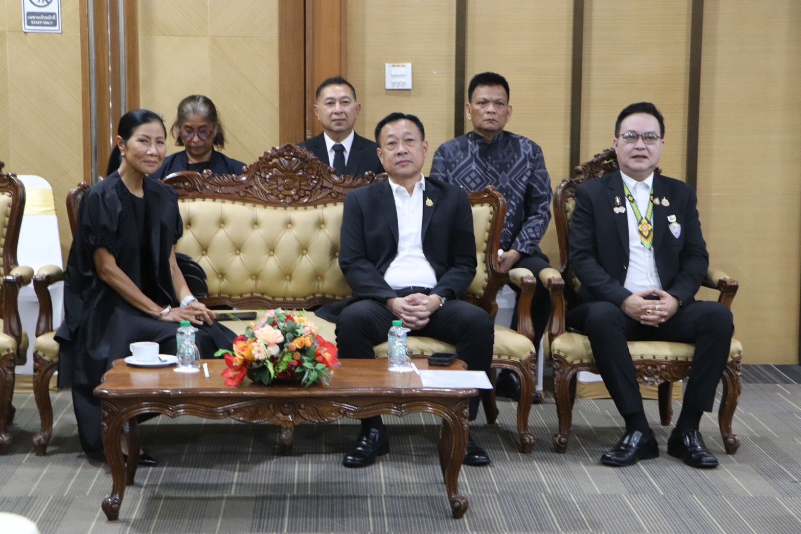Five individuals, mostly men in suits, sitting formally for a photo.