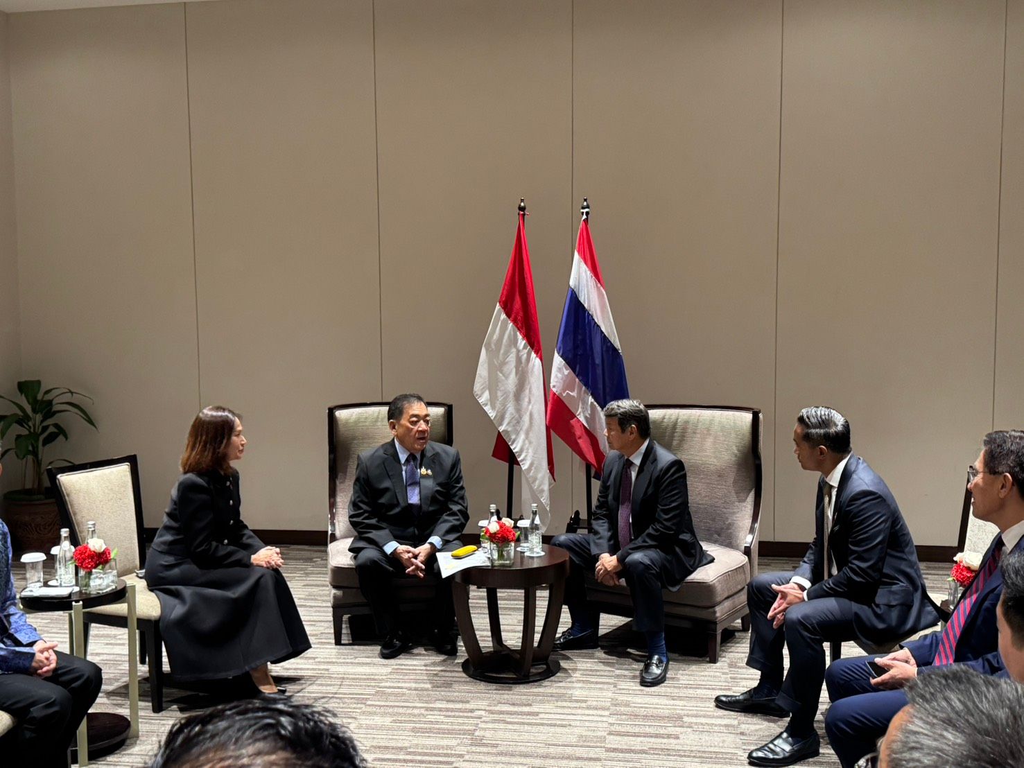 Officials from Indonesia and Thailand meet in a room with their national flags.