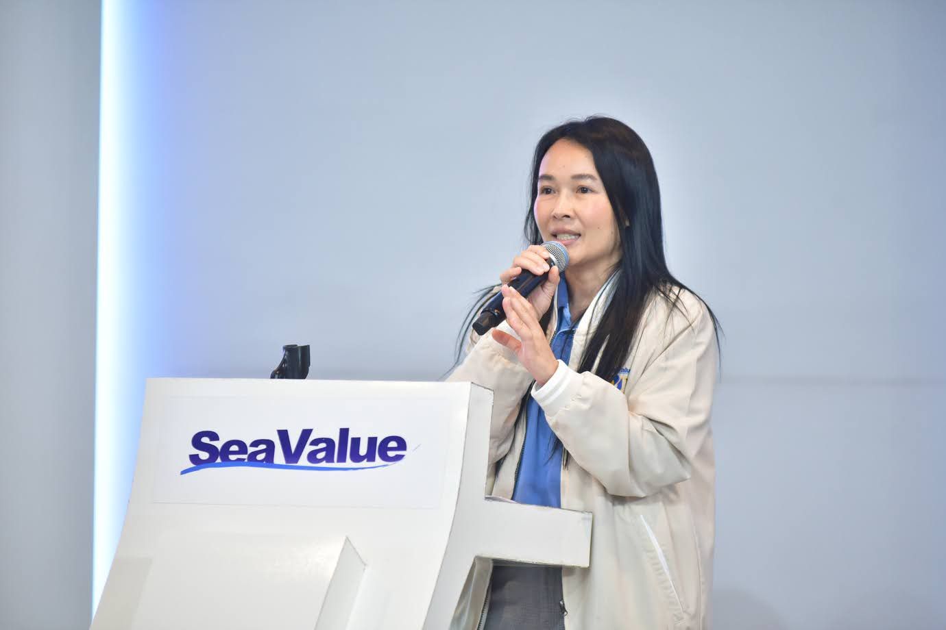 Woman speaking into microphone at a SeaValue podium during a presentation.