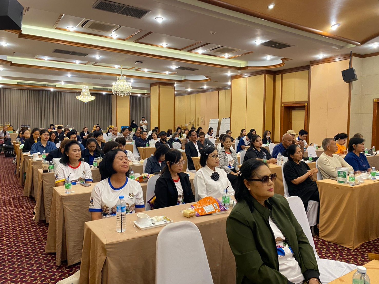 Audience attentively listening during a conference in a well-lit meeting room.