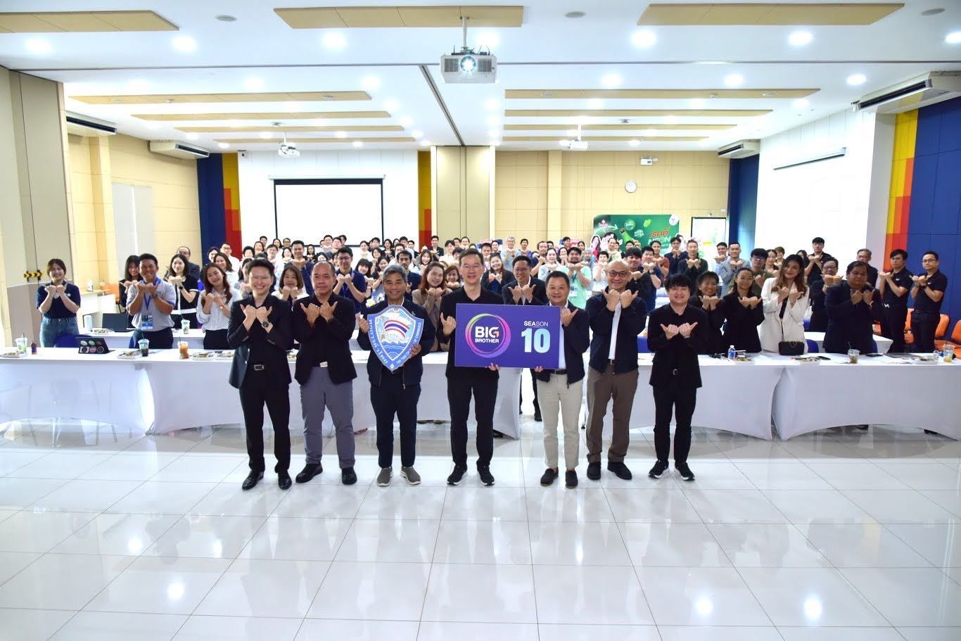 A group of people holding a 'BHS 10' sign in a brightly lit conference room.