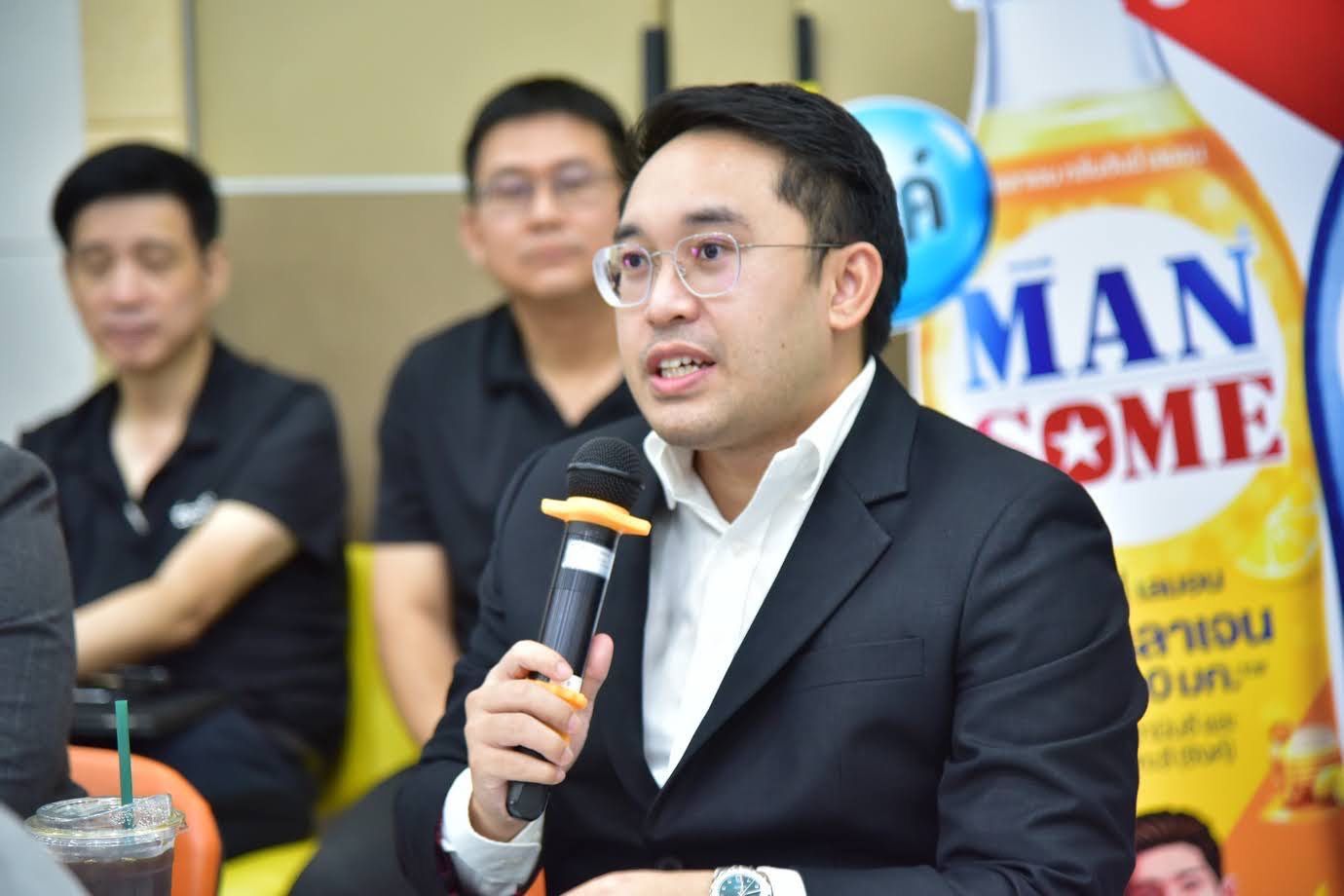 A man in glasses and a suit speaks into a microphone during a presentation.