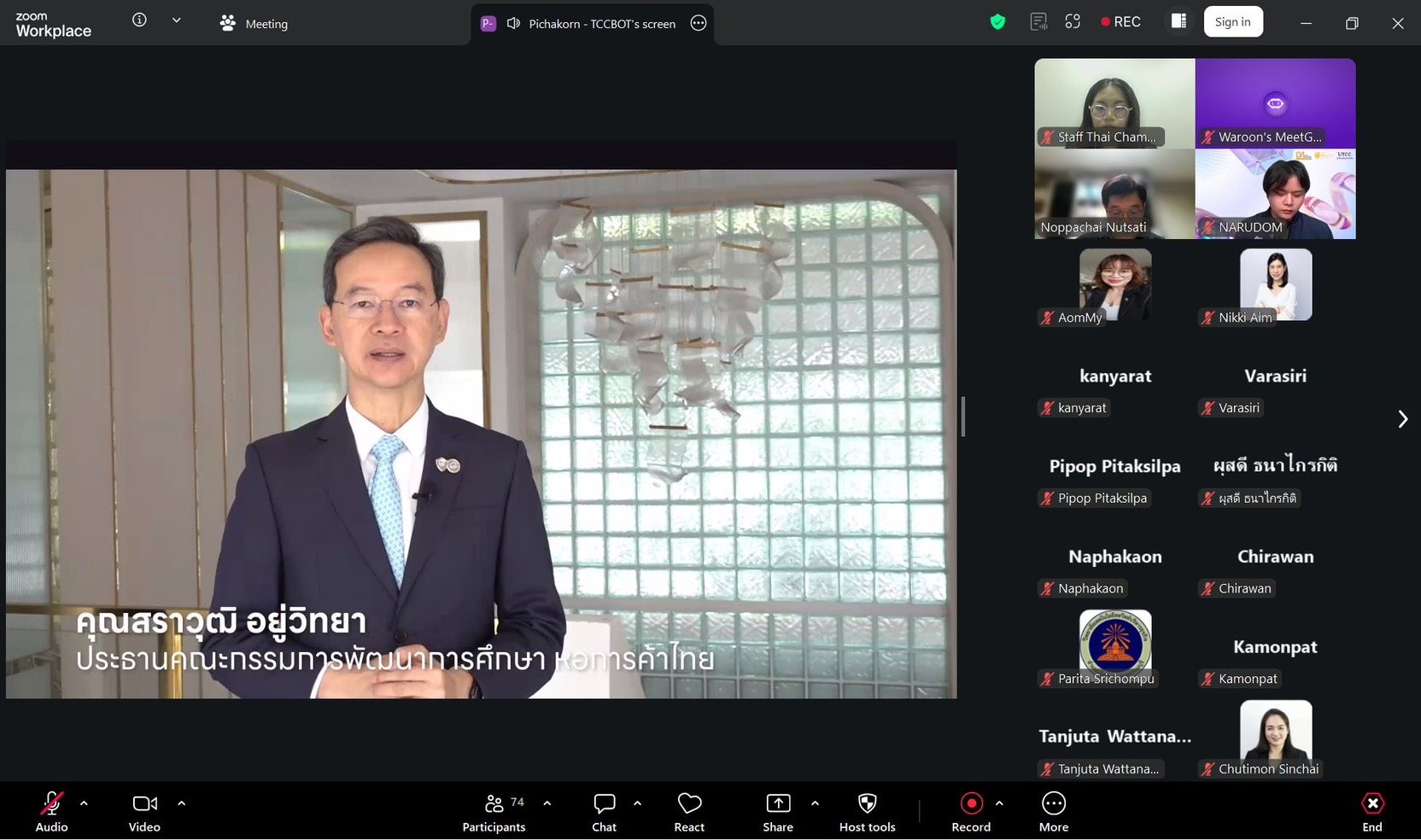Man in suit speaks during a virtual conference call with multiple attendees displayed.
