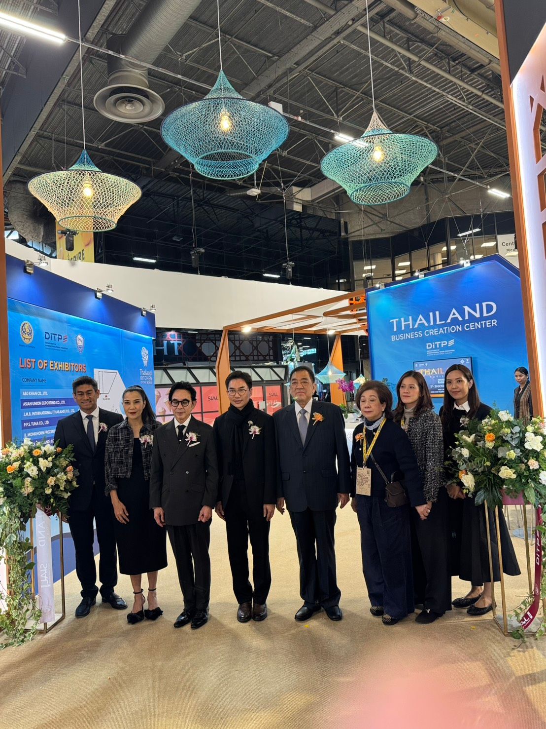 Group of professionals posing at a vibrant Thailand exhibition booth.