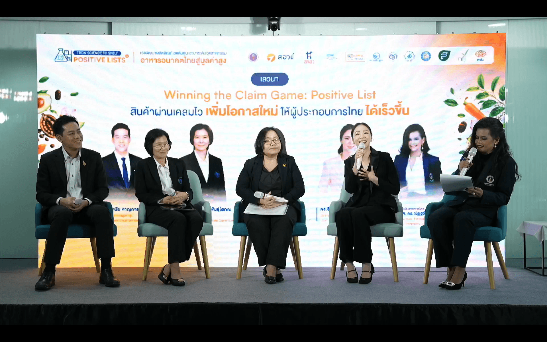 Panel discussion with six people onstage, screen shows 'Winning the Claim Game: Positive List.'