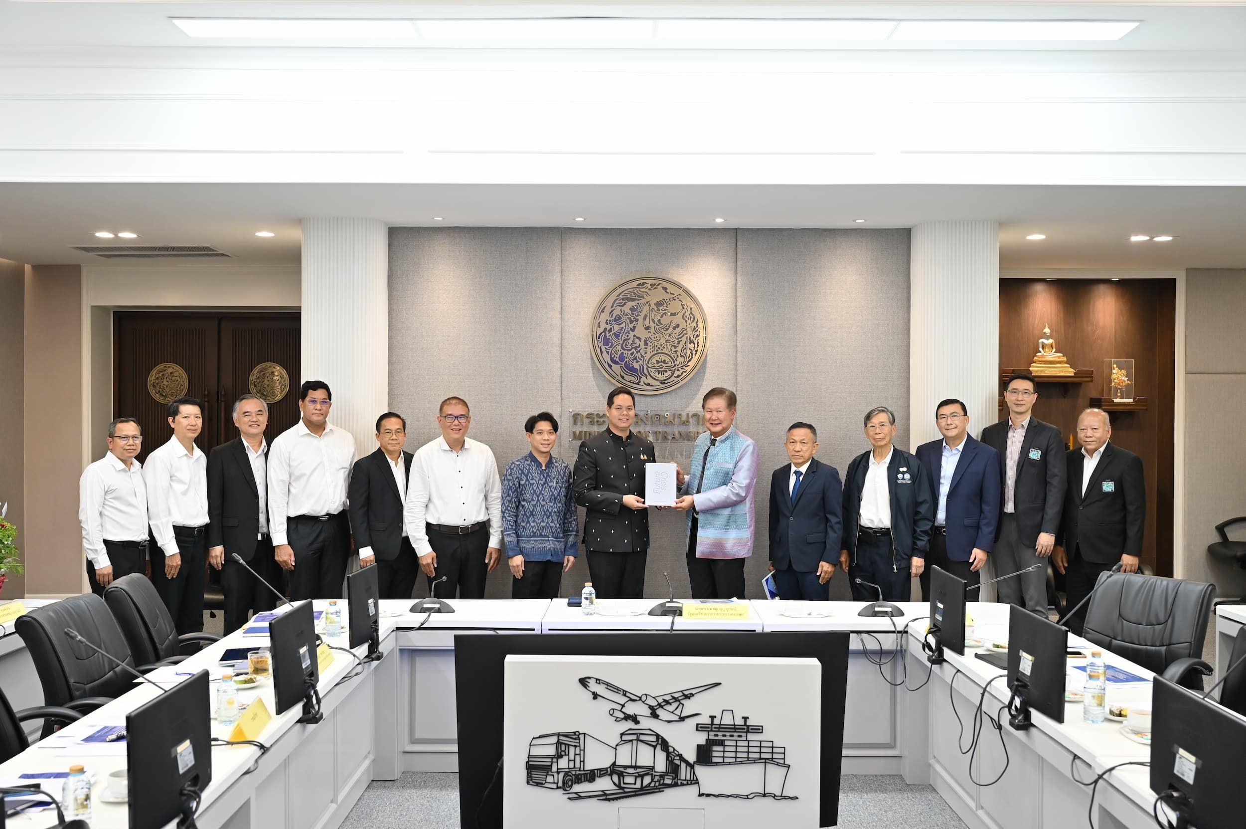 Group of officials shaking hands over a document in a formal meeting room.