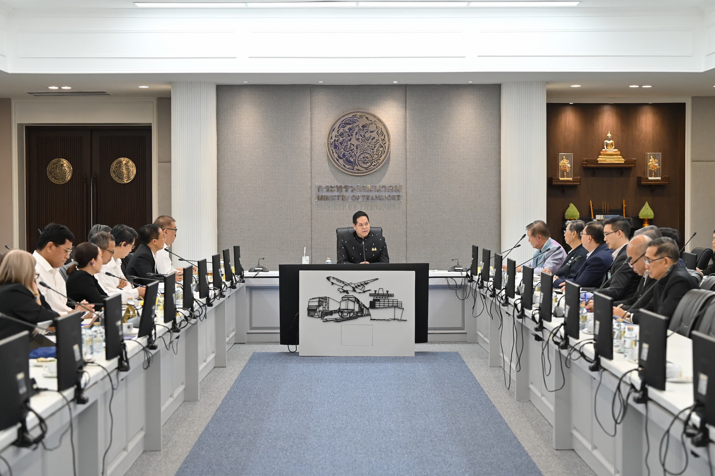 A formal meeting with professionals seated around a large U-shaped conference table.