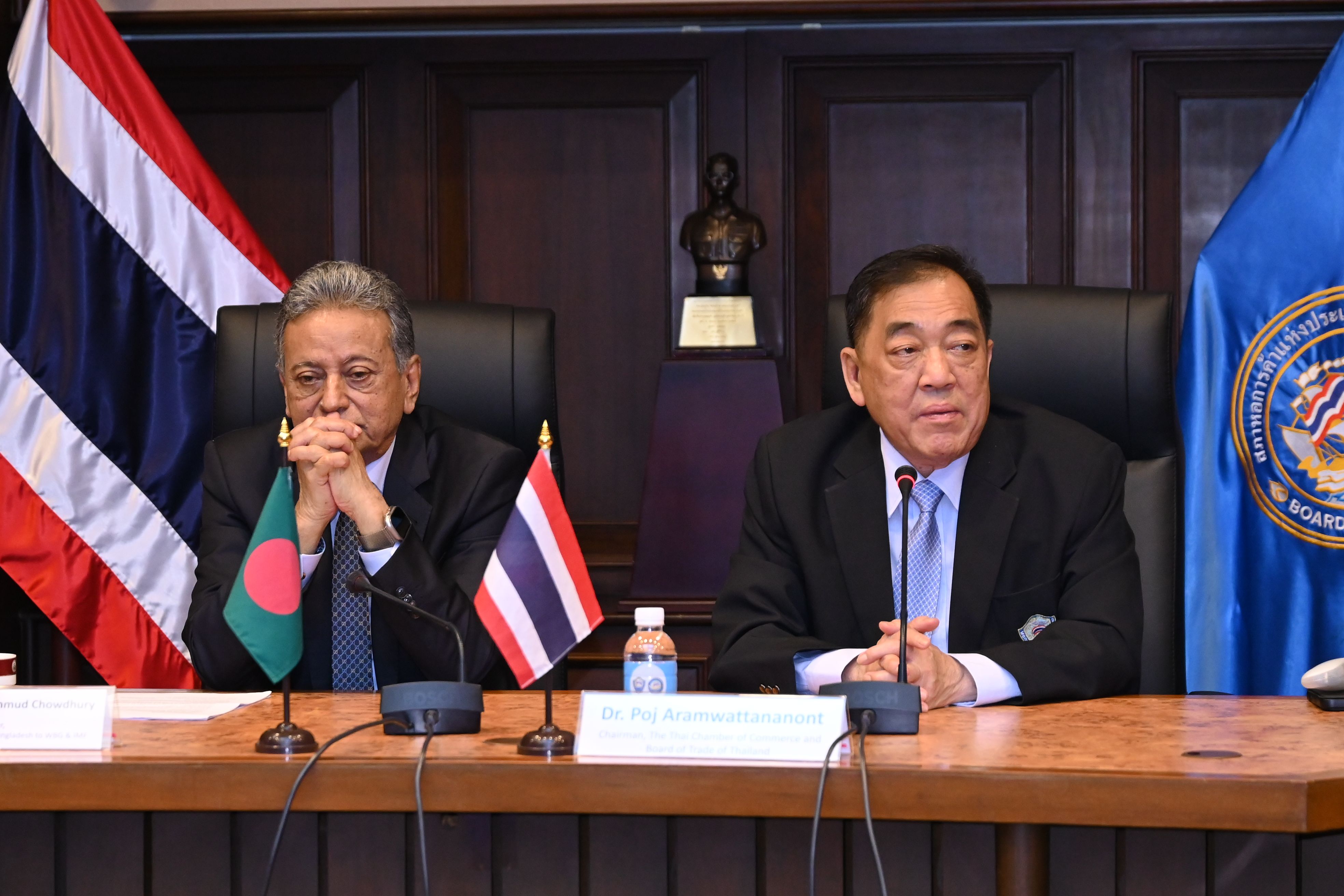 Two diplomats in suits sit at a conference table with flags of Thailand and Bangladesh.