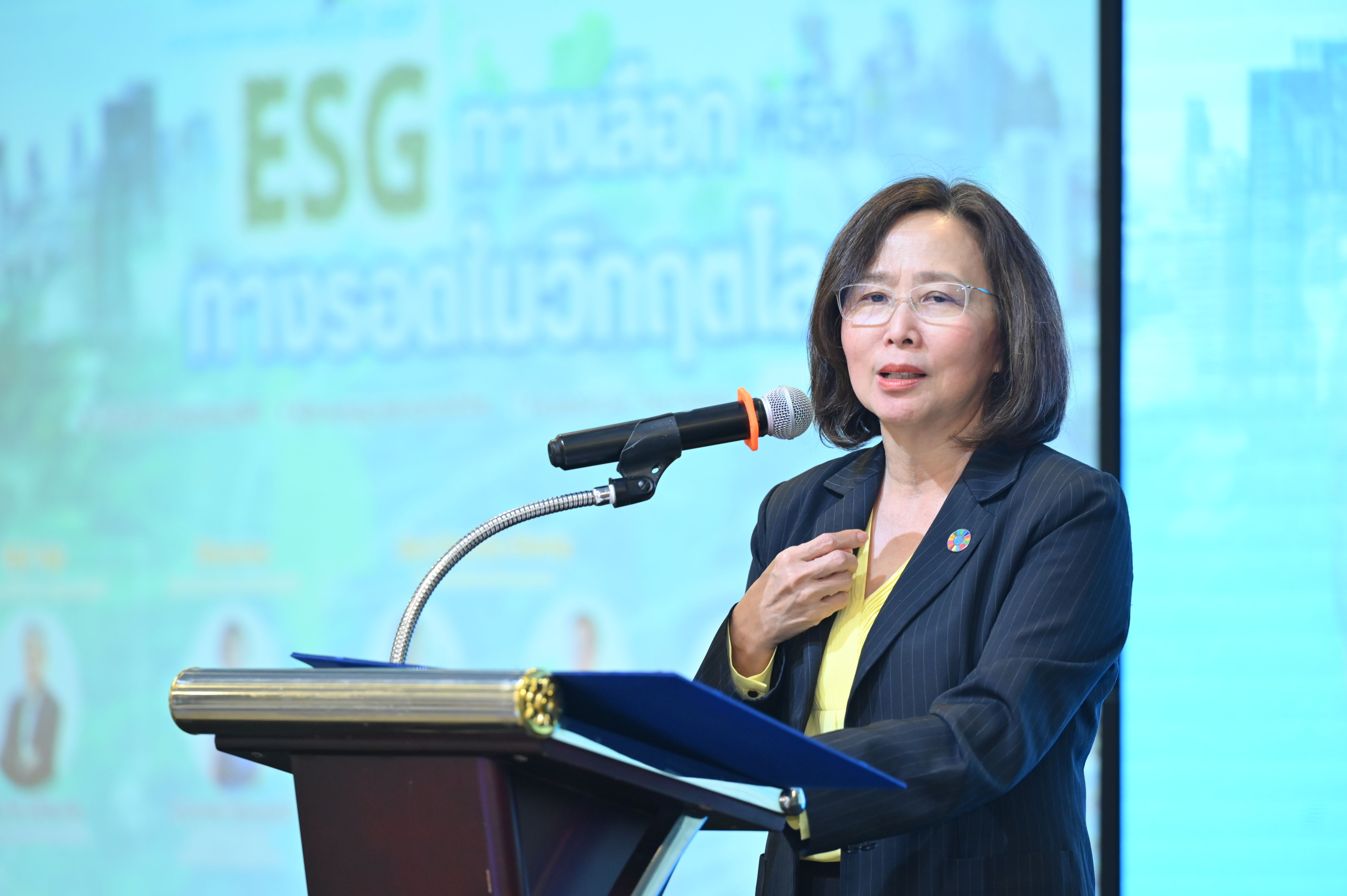 Woman in blazer speaks at a podium with a microphone at an ESG event.