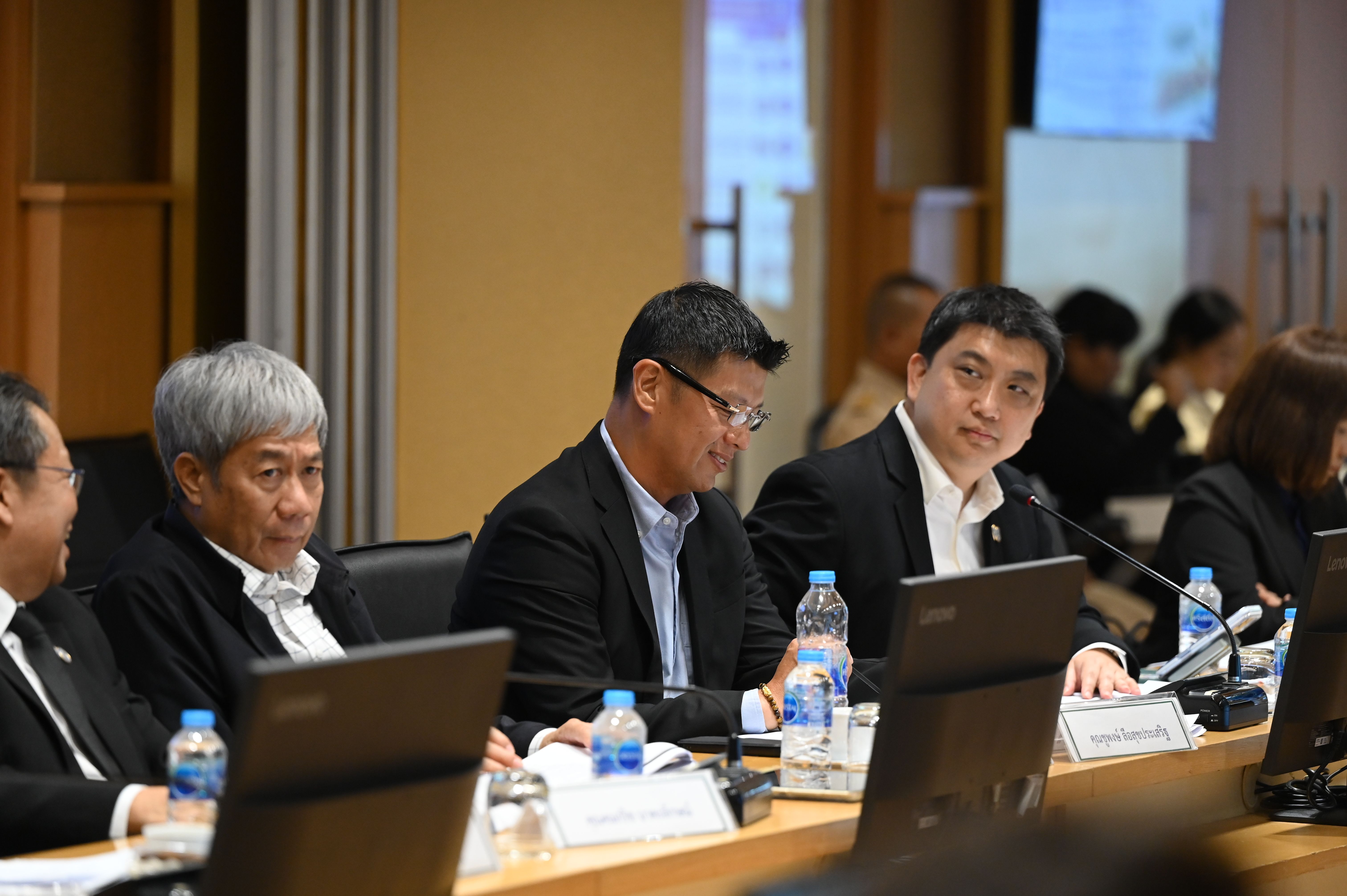 Men in business attire attend a conference meeting at a long table with laptops.