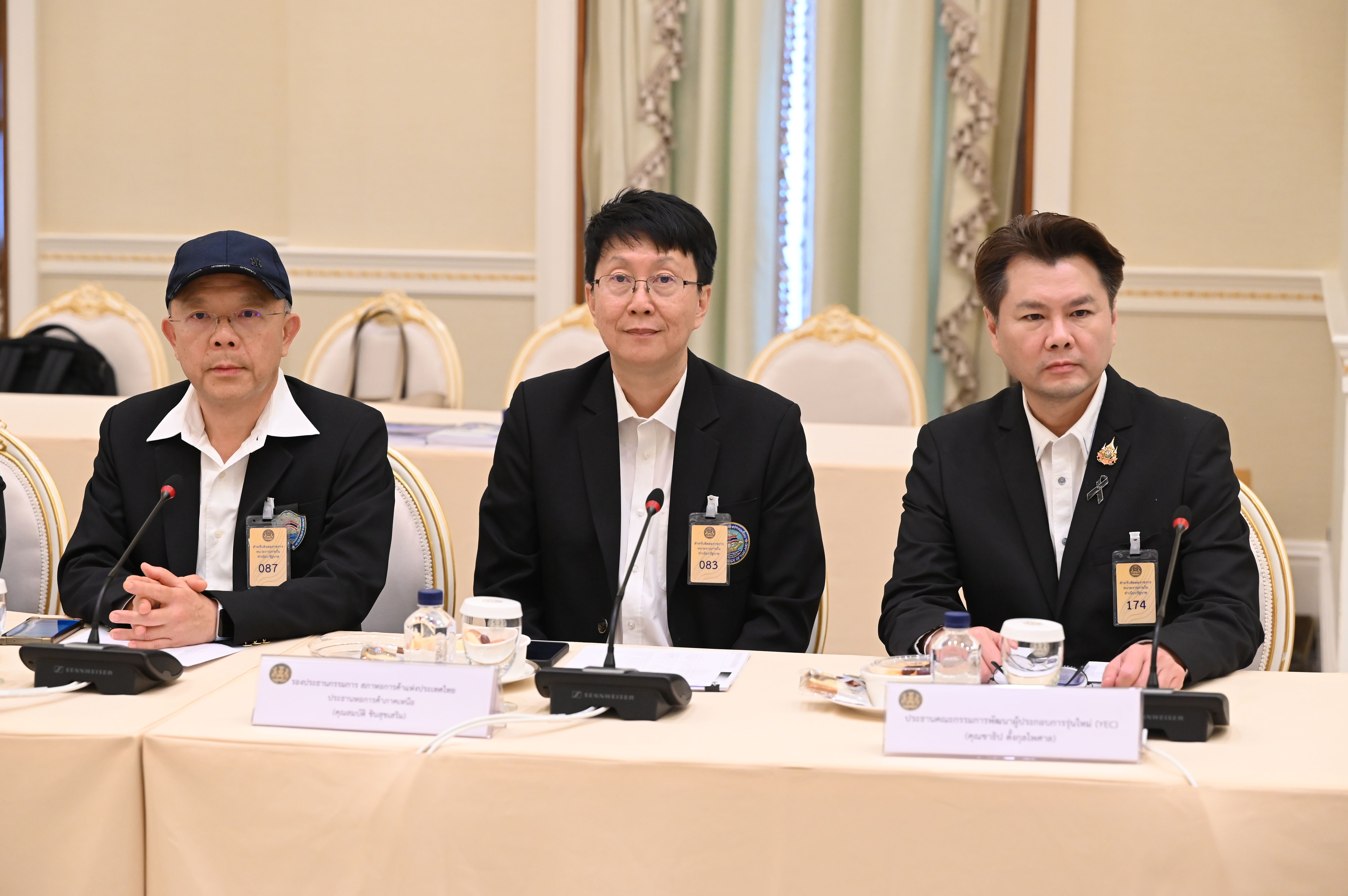 Three professionals, including a woman in glasses, sit attentively at a meeting table.