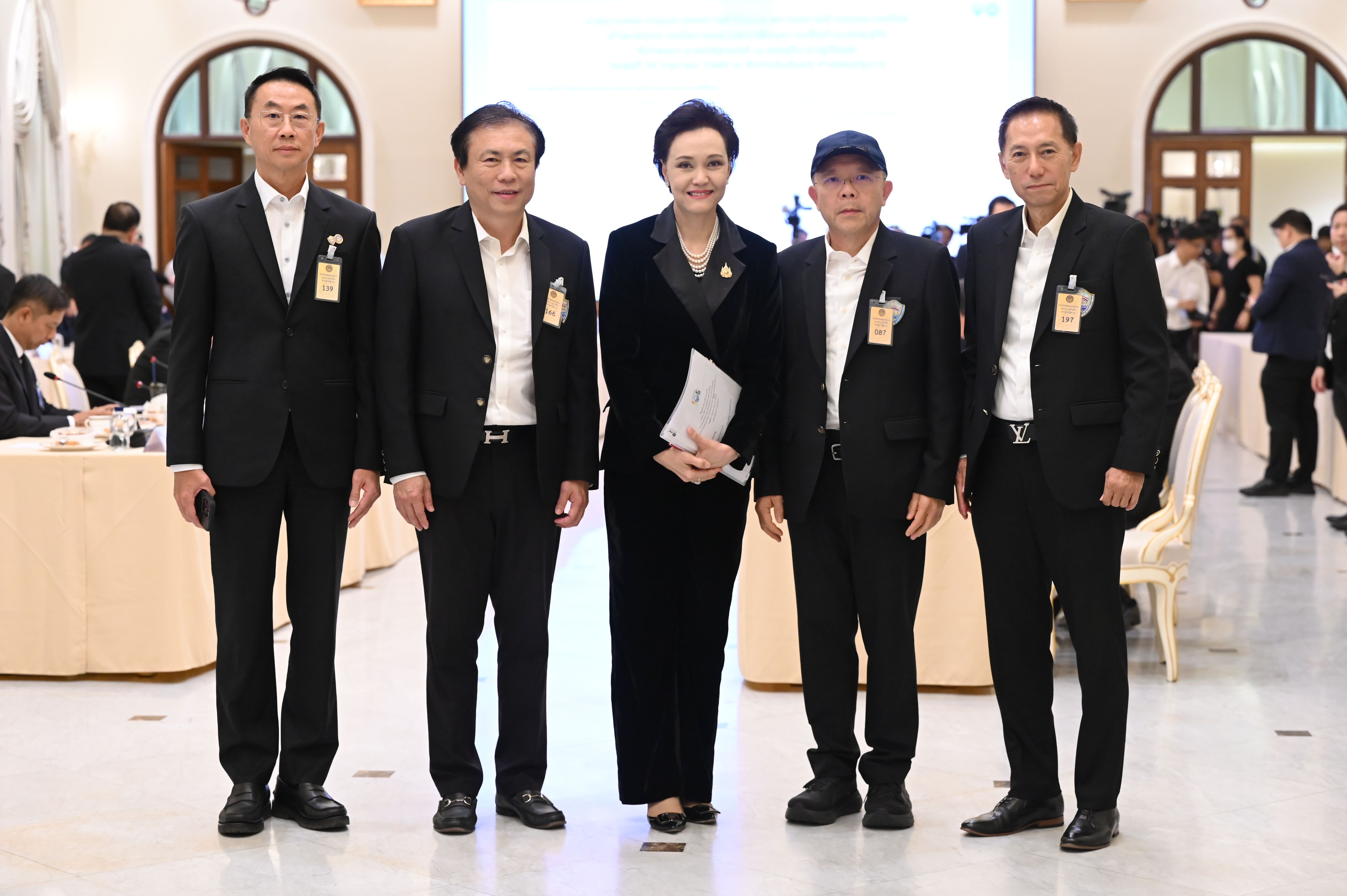 Five Thai officials, including one woman, pose for a group photo at an indoor event.
