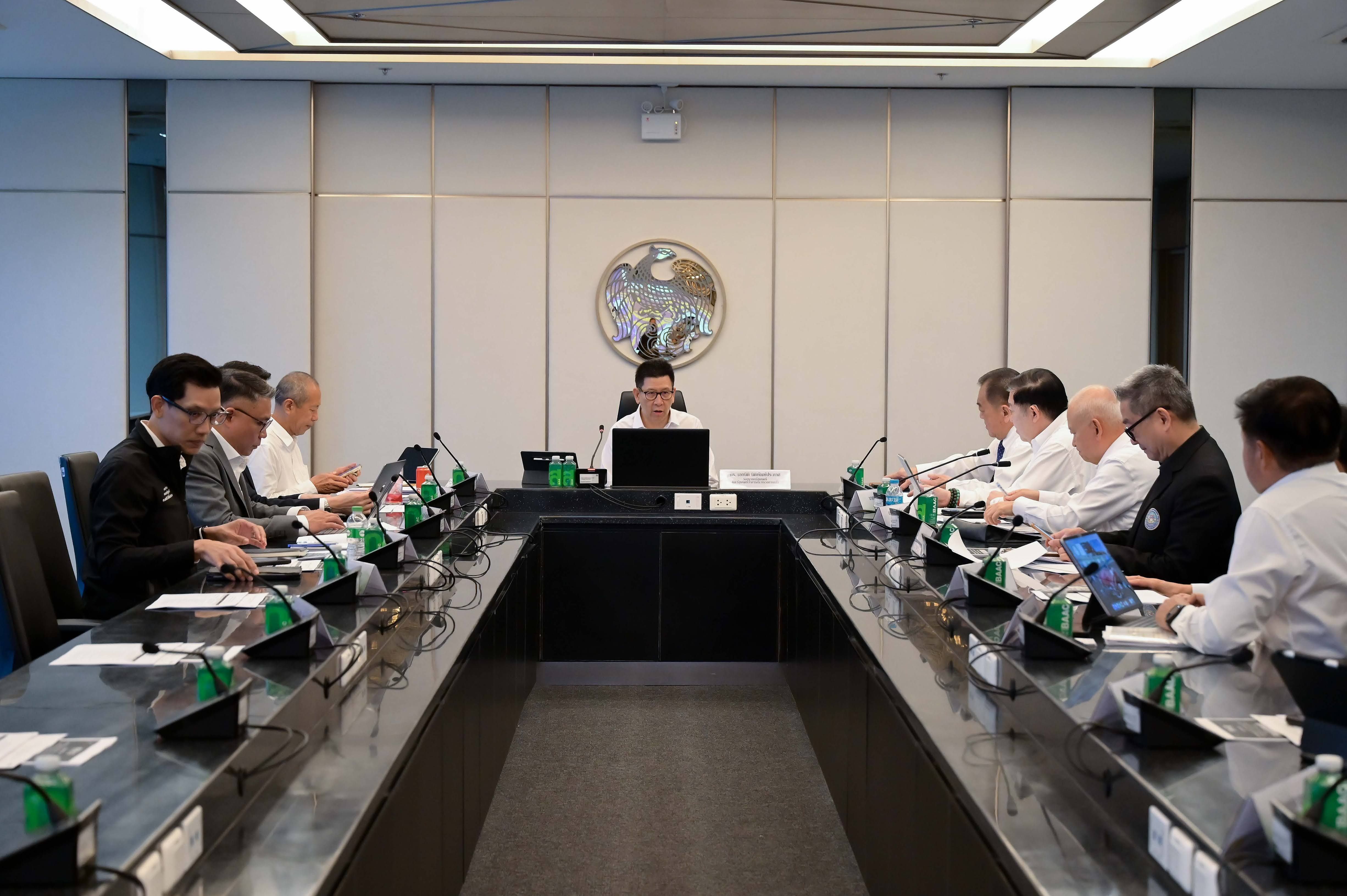 Professionals gather around a U-shaped conference table in a formal meeting room.