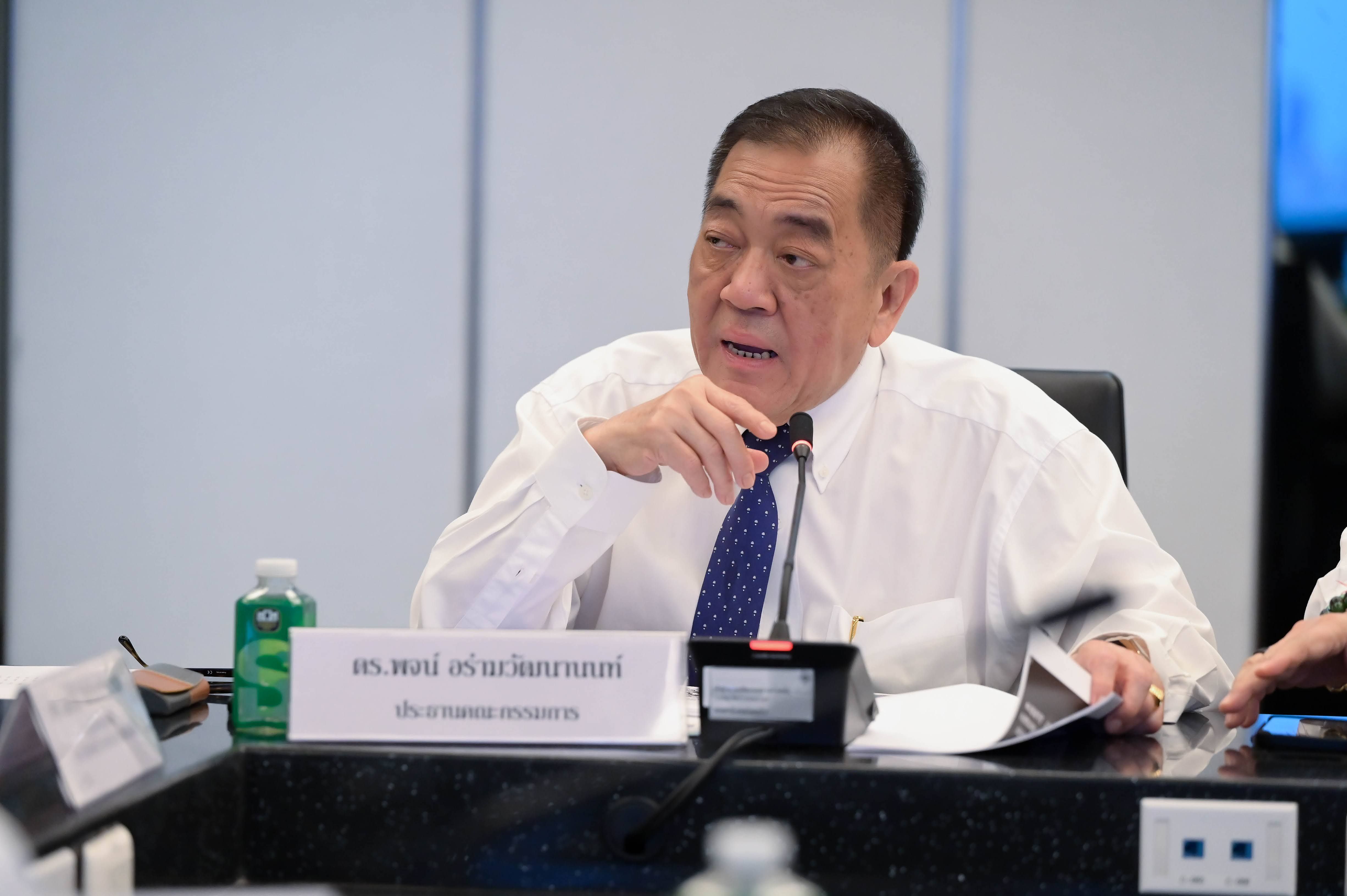 Man in white shirt and blue tie speaks at a conference table.