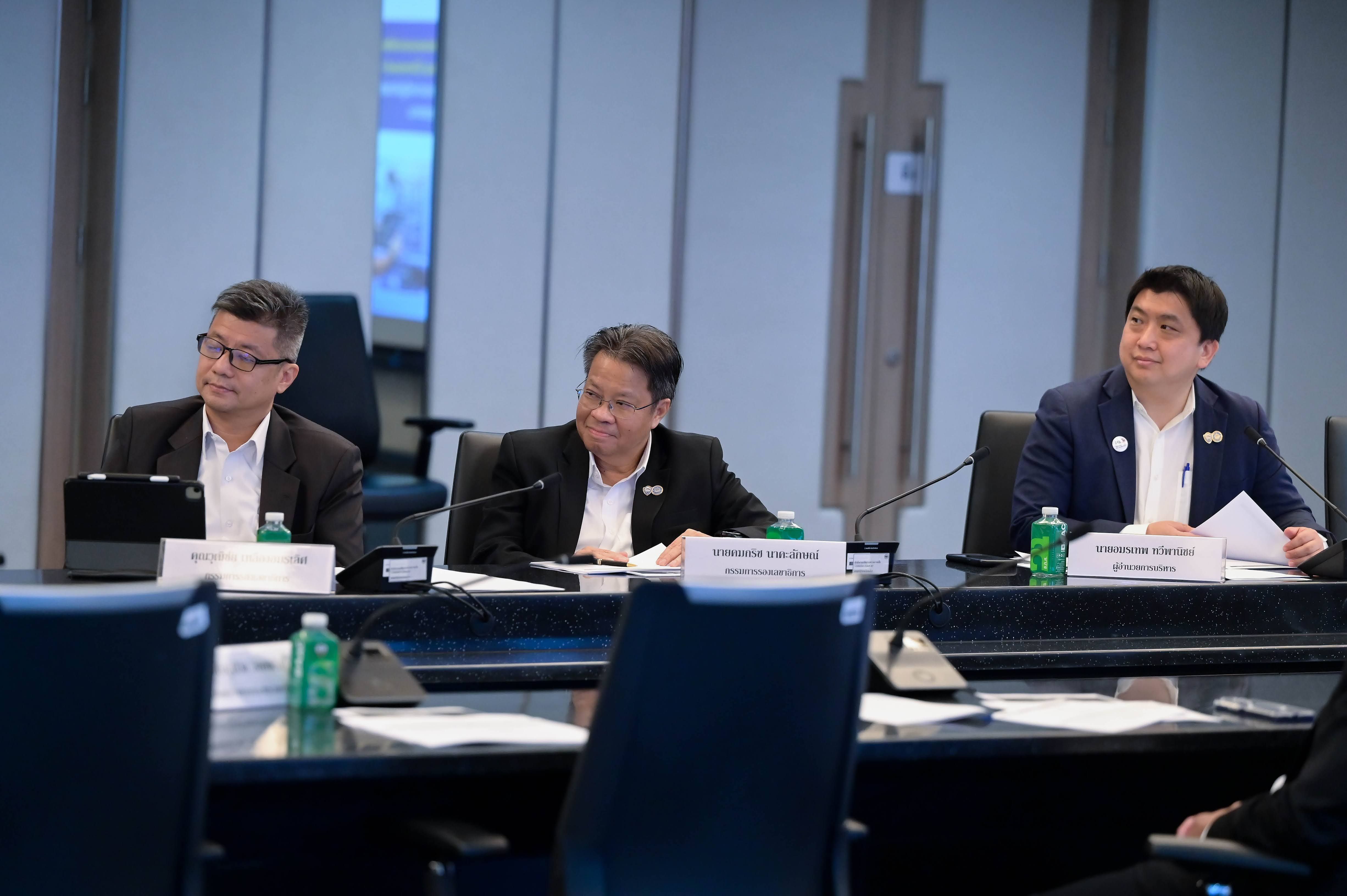 Three professionals in business attire sit attentively at a conference table during a meeting.