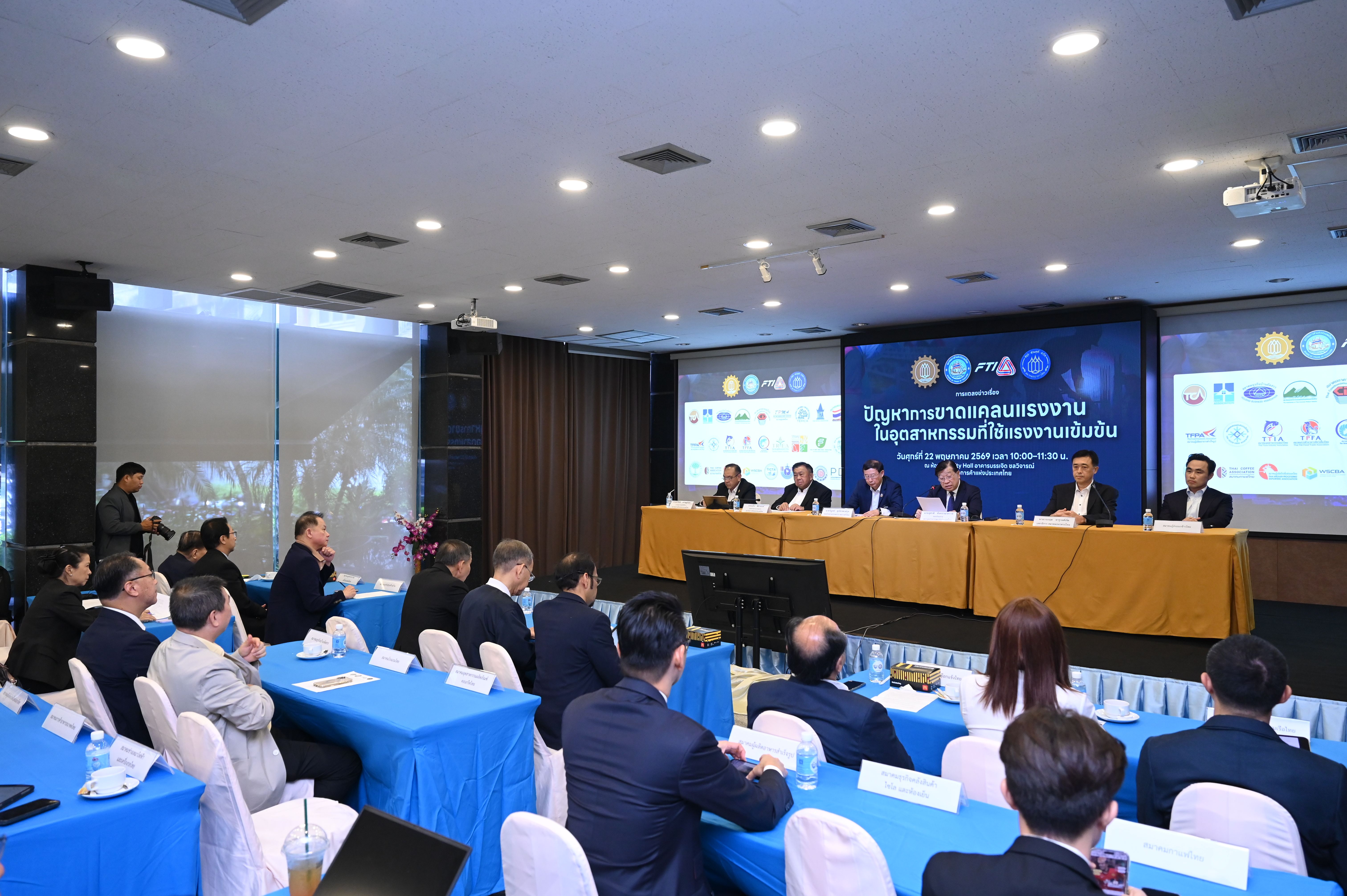 Panel of speakers addressing an audience at a formal conference or seminar.