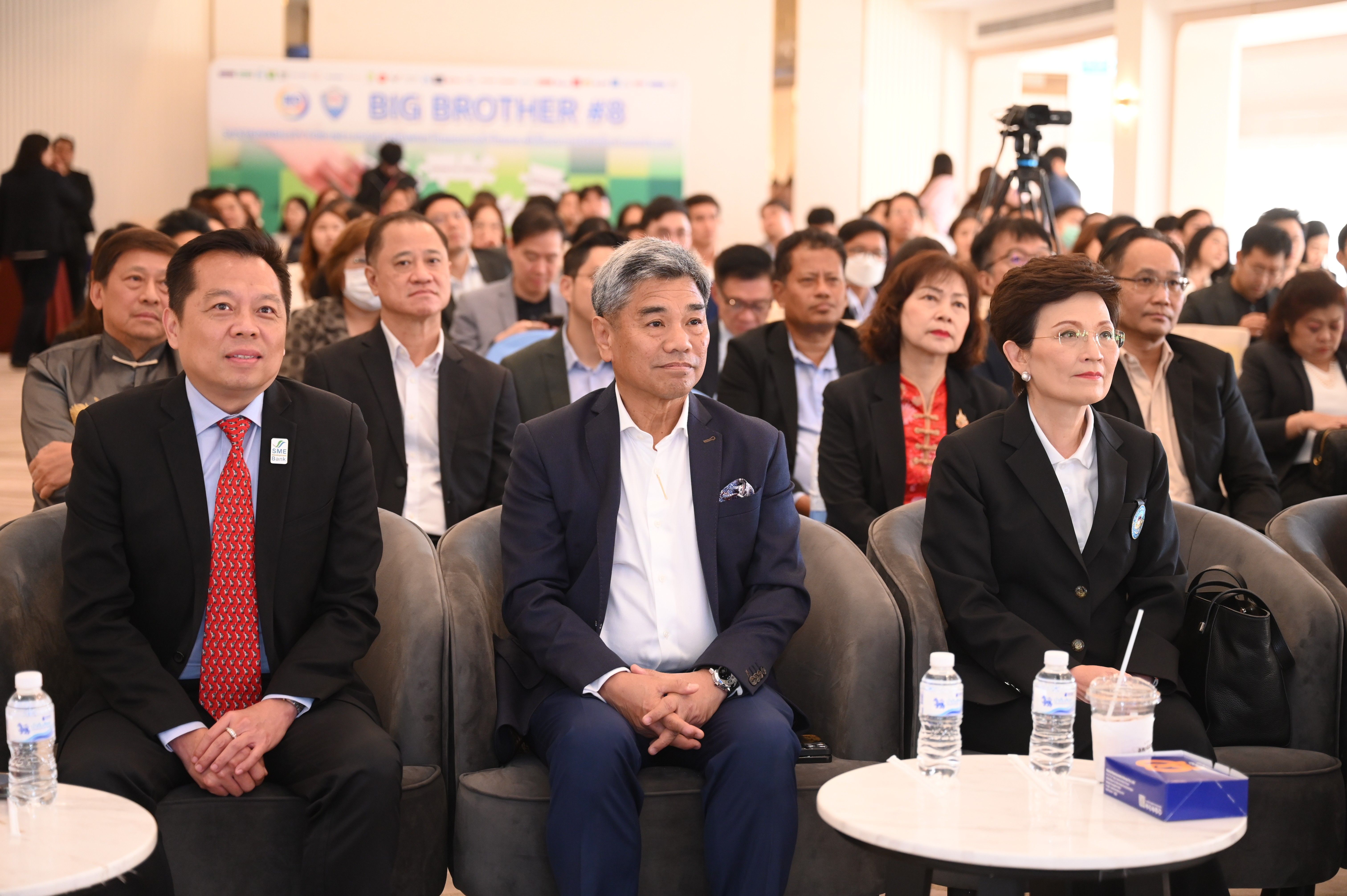 Three Asian professionals seated in an audience at a business conference.