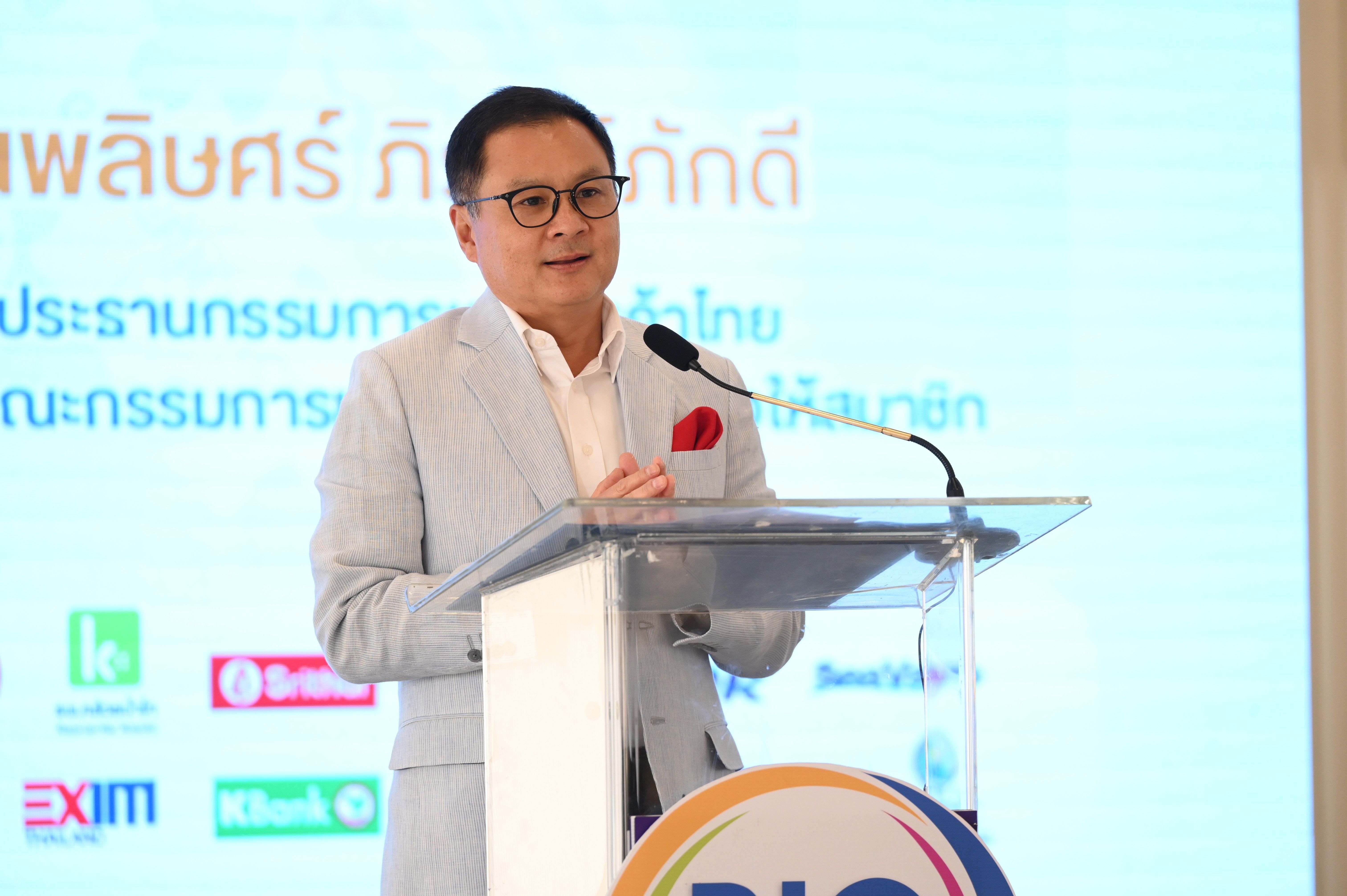 A man in glasses speaks at a podium with a microphone at a business event.
