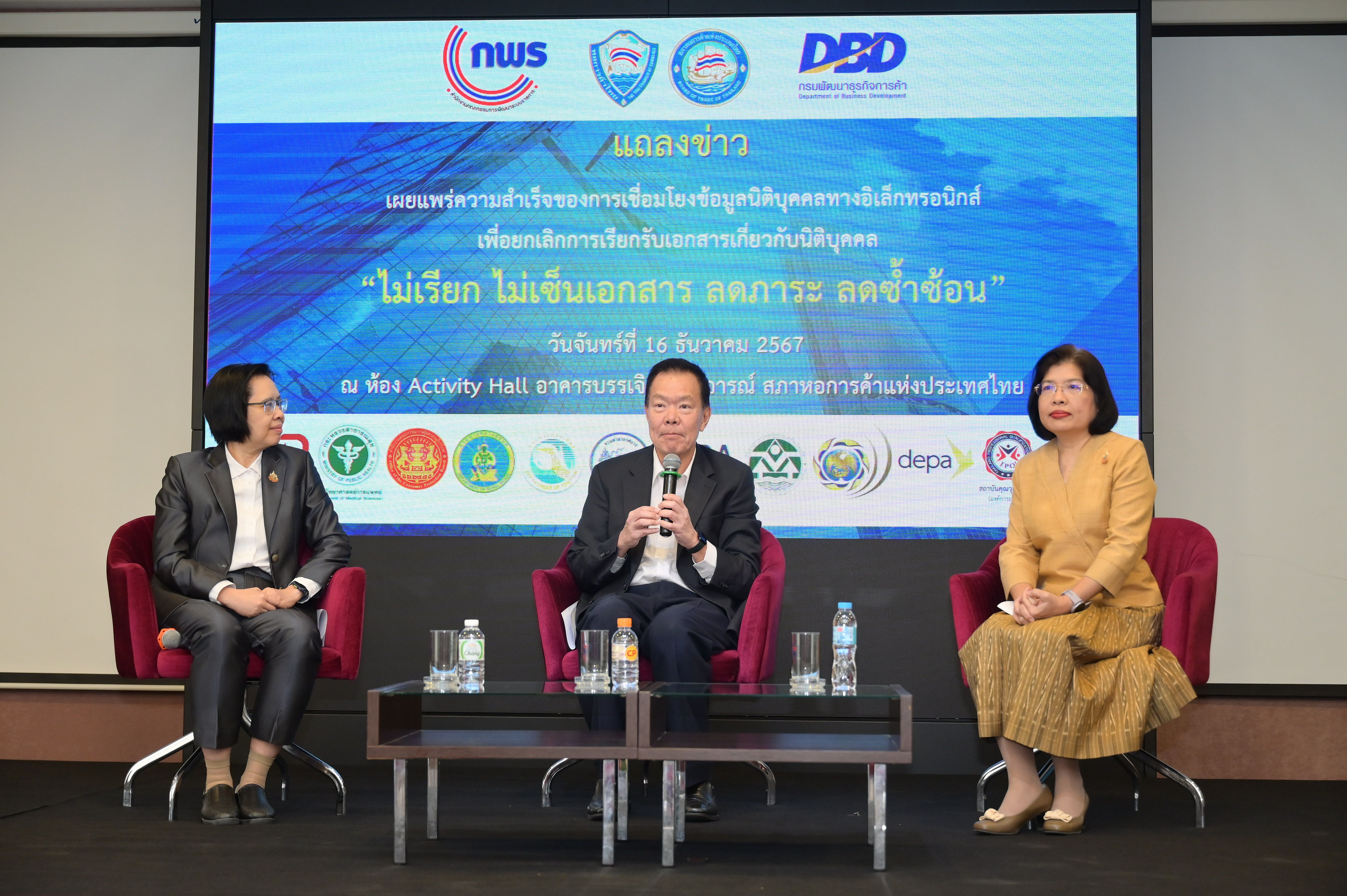 Three panelists, a man speaking into a microphone and two women, are seated on a stage.
