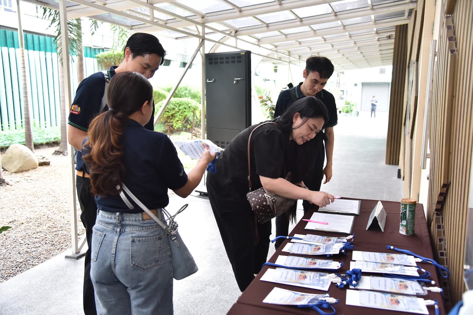 Four people sign in at an outdoor event registration table, collecting badges.