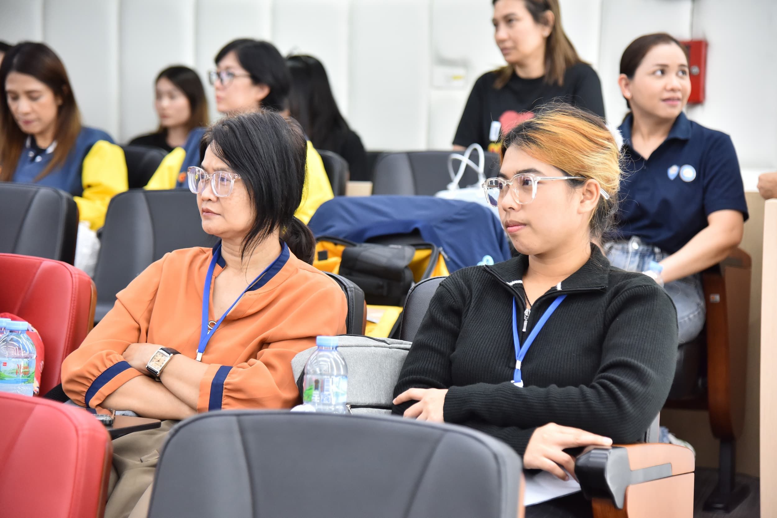 A group of women, some wearing glasses, sitting attentively in a meeting or seminar.