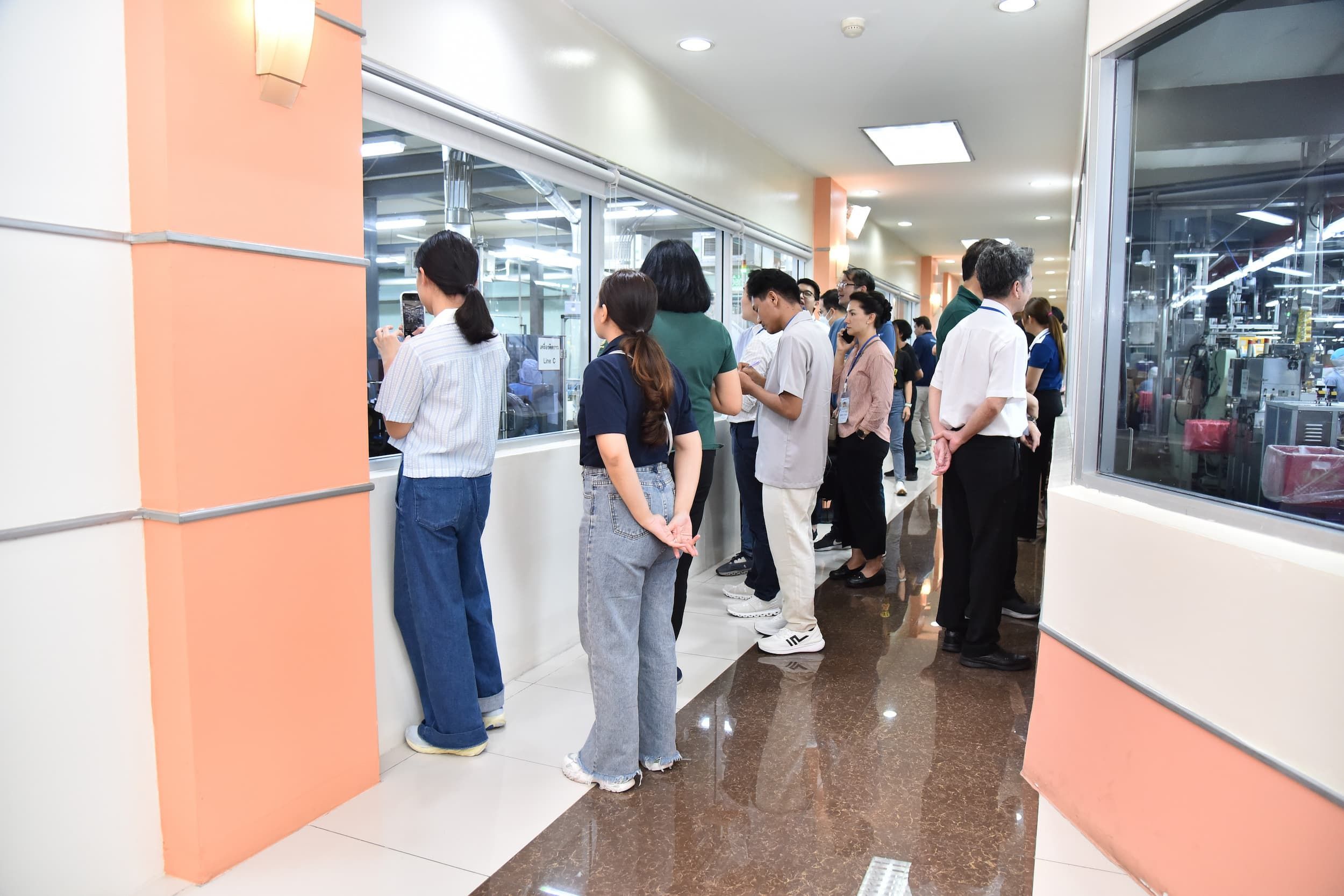 A group of people standing in a brightly lit hallway, looking into display windows.