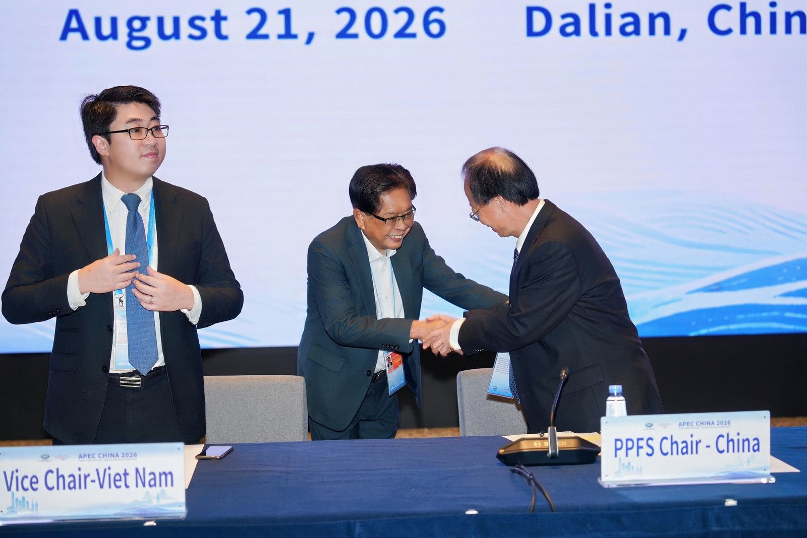 Two officials shake hands at a formal PPFS meeting in Dalian, China.