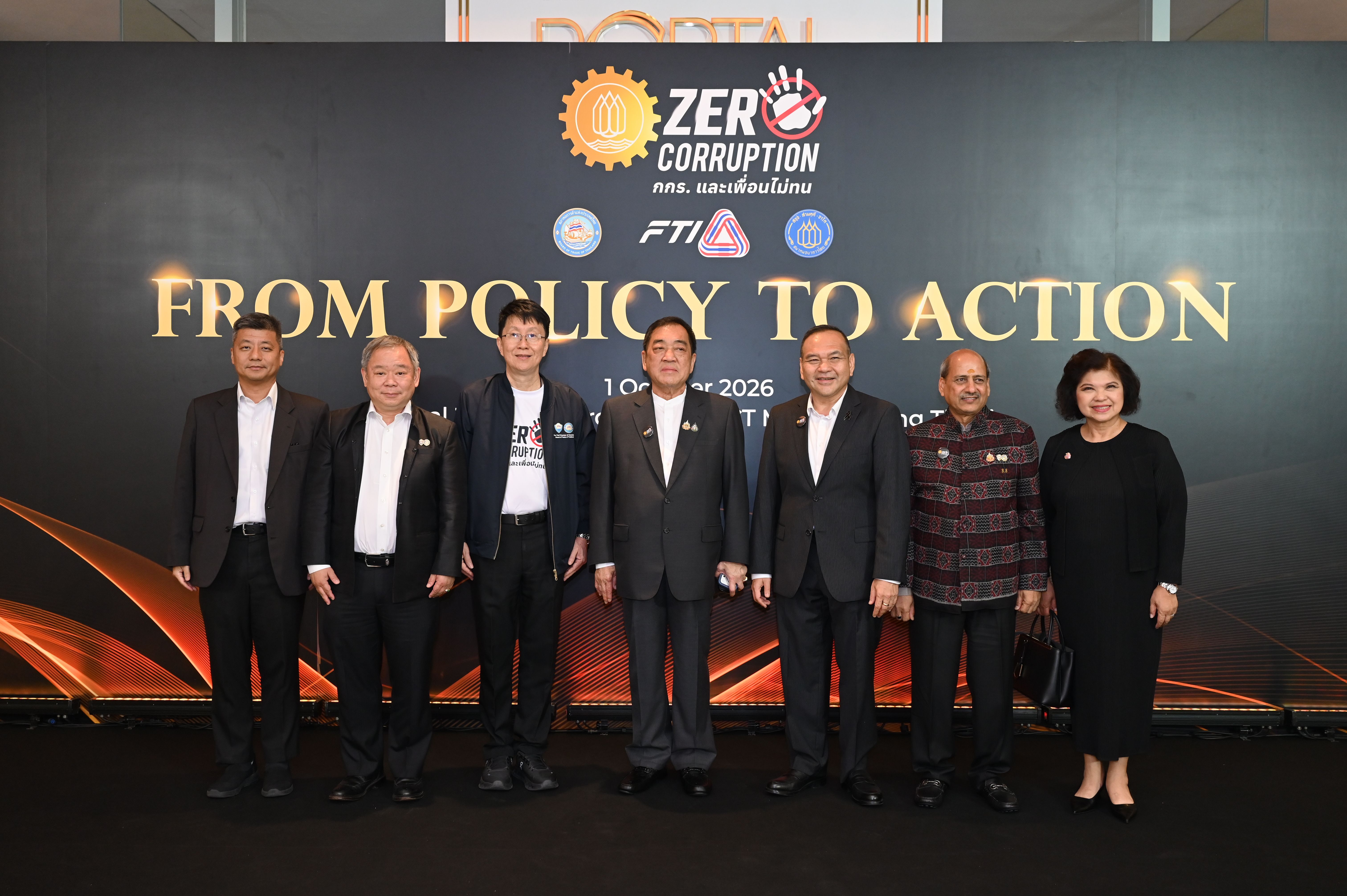Seven people stand formally in front of a 'Zero Corruption' and 'From Policy to Action' banner.