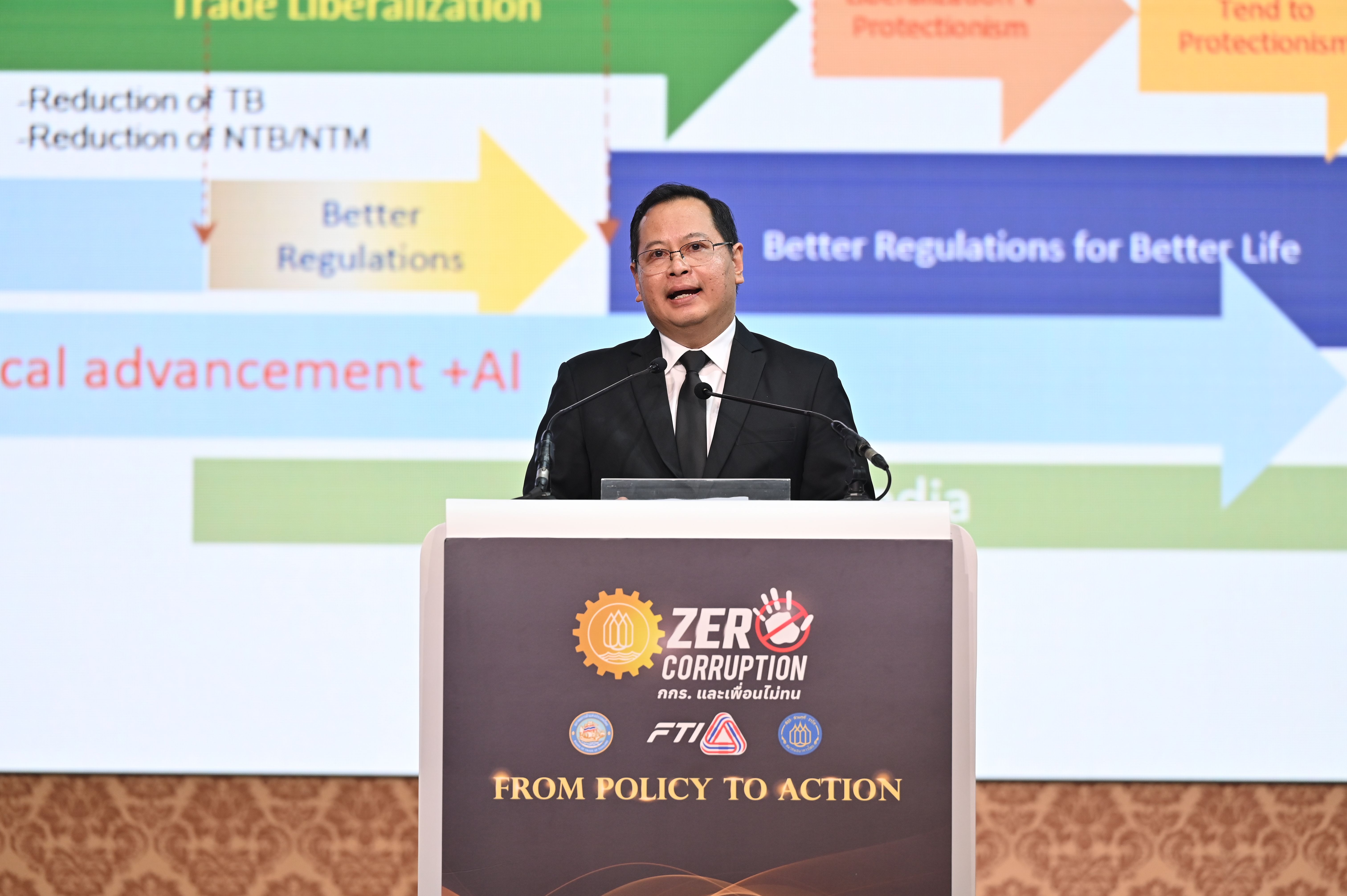 Man in suit speaks at podium during a conference on trade and better regulations.