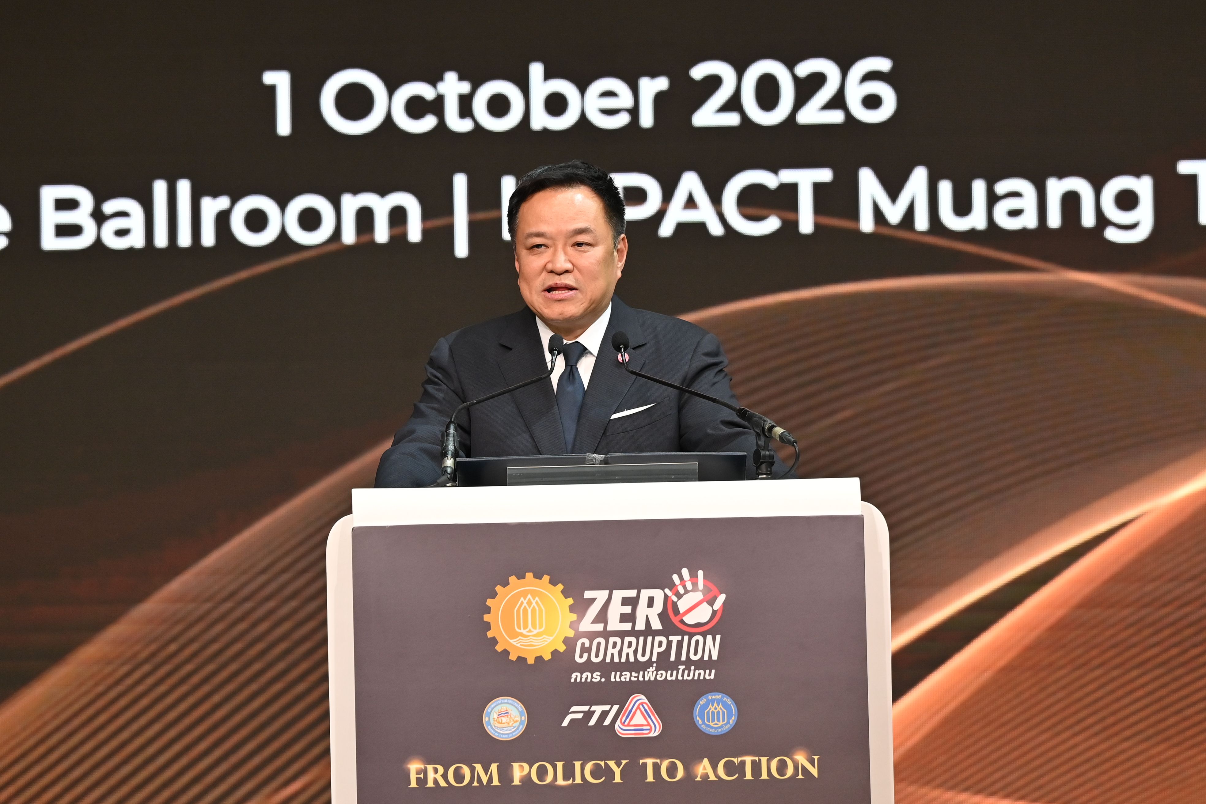 A speaker addresses an event from a podium with a 'Zero Corruption' logo.