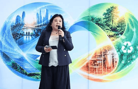 Professional woman speaking at a conference with a backdrop illustrating sustainable development themes.