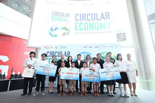 A group of adults and students pose with awards in front of a 'Circular Economy' banner.