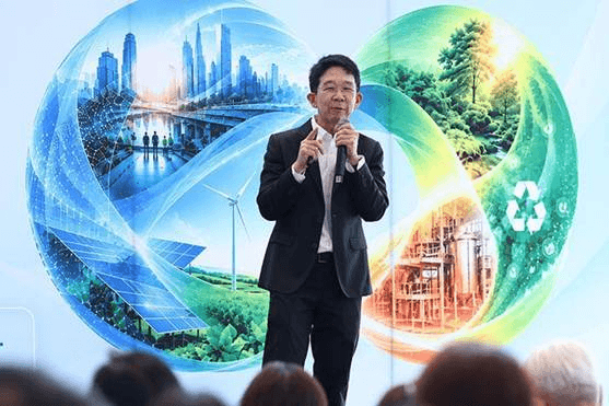 Man speaks before a screen displaying a graphic of sustainable city and natural environments.