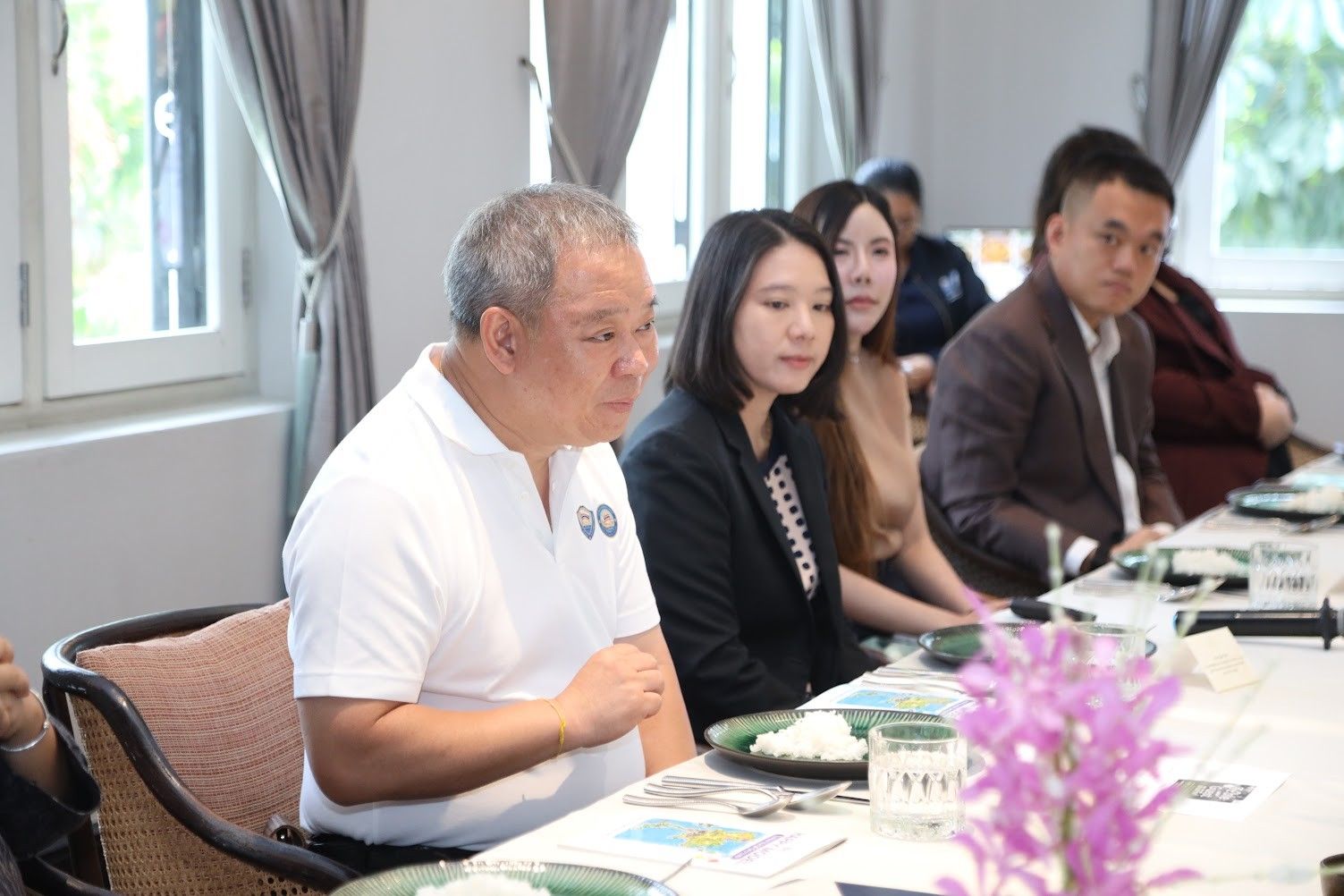 Group of professionals seated at a table, attentively listening during a business gathering.
