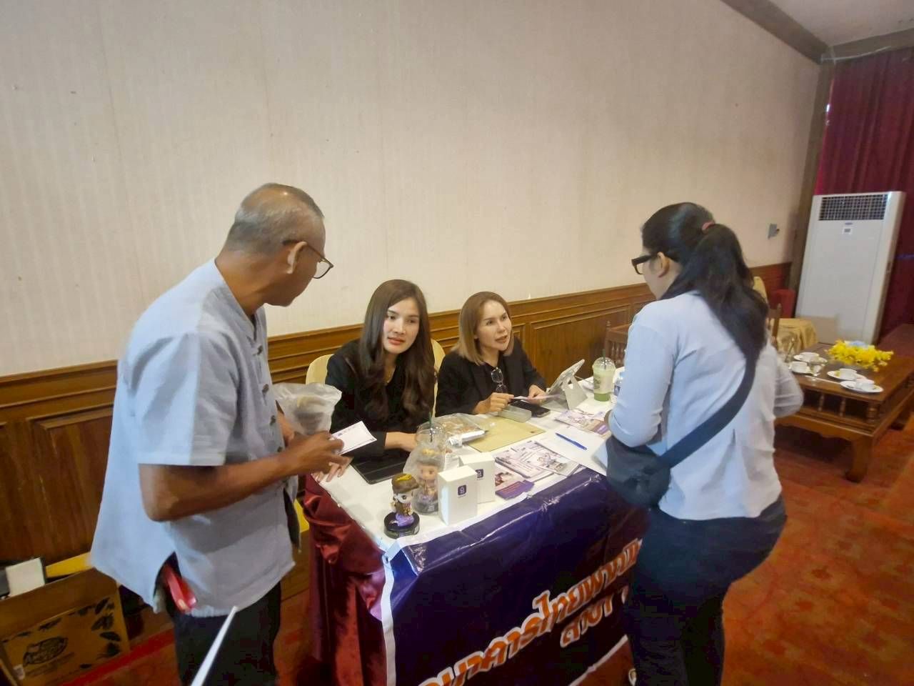 People gather at an information booth, with two staff members assisting attendees.
